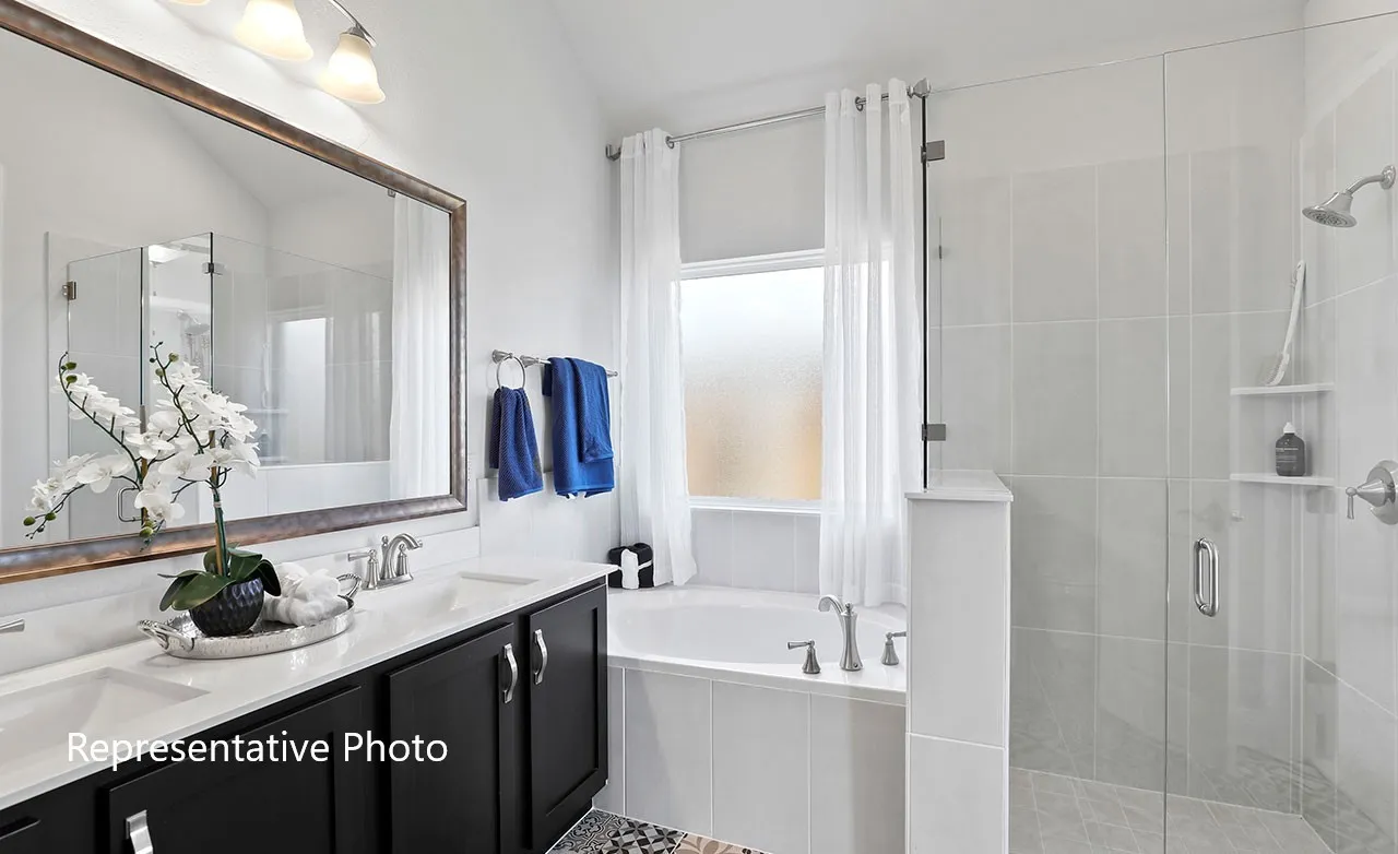 Bathroom featuring a double vanity with dark cabinetry, integrated dual sinks, and a large framed mirror