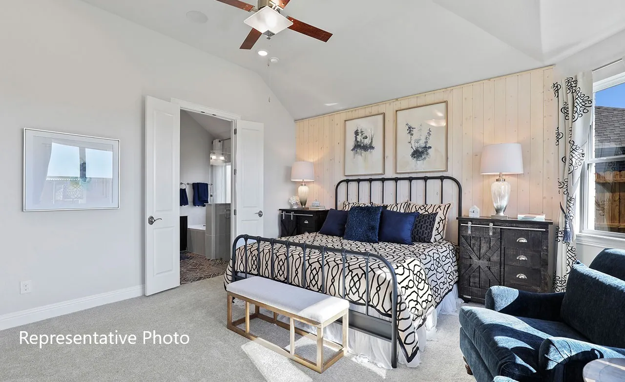 Vaulted ceiling bedroom featuring carpet flooring, shiplap accent wall, ceiling fan, and double doors opening to a bathroom