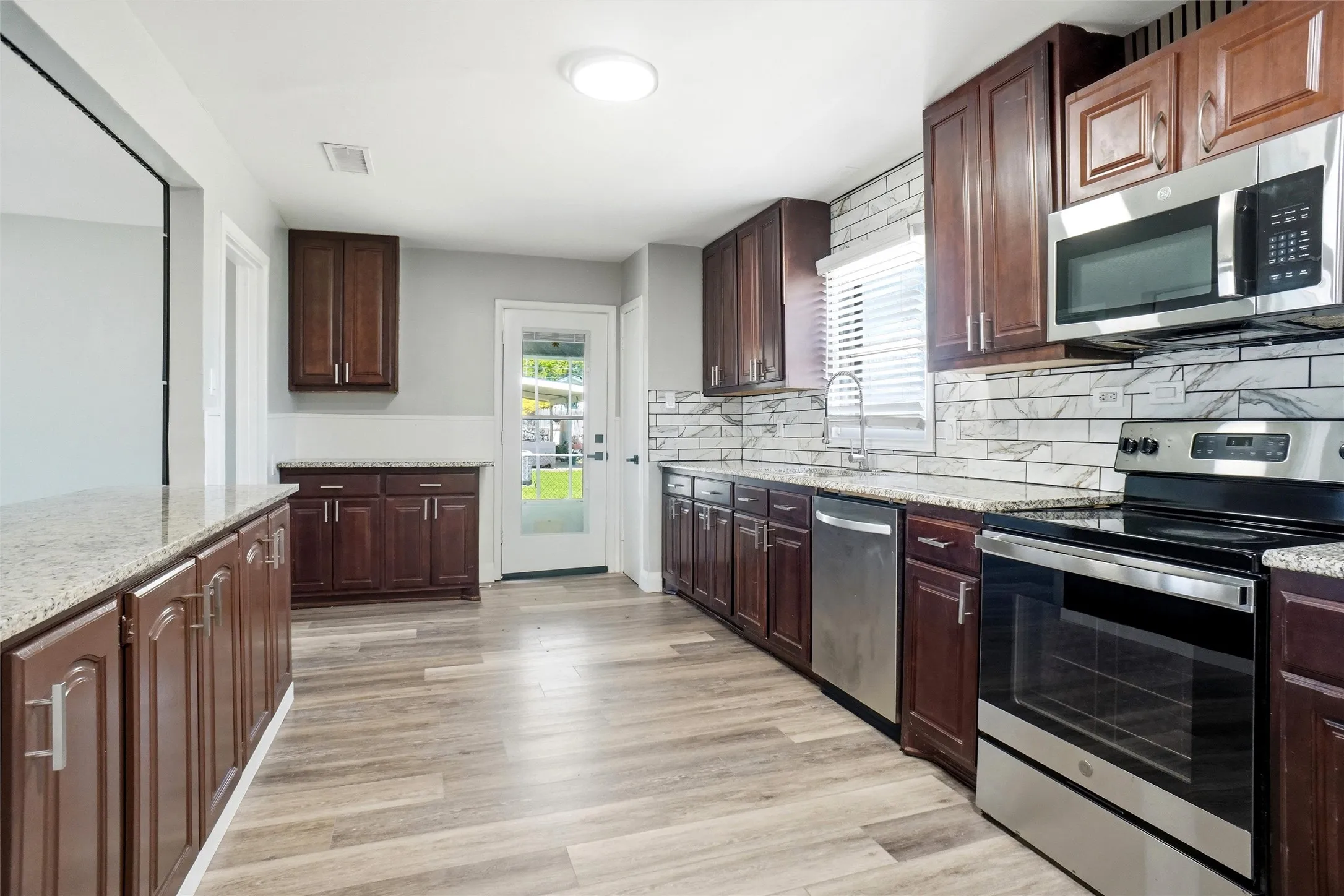 breakfast bar, loads of cabinets, granite counters, stainless appliances, coffee bar next to back door to covered back porch