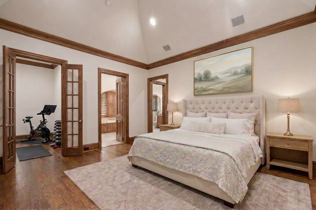 Vaulted ceiling, hardwood flooring, wood-finish trim, double French doors, and an additional doorway