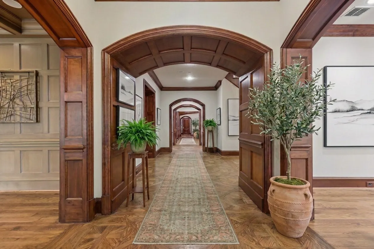 Current hardwood flooring with a decorative inlay pattern, arched doorways, detailed wood paneling, and an coffered wood ceiling