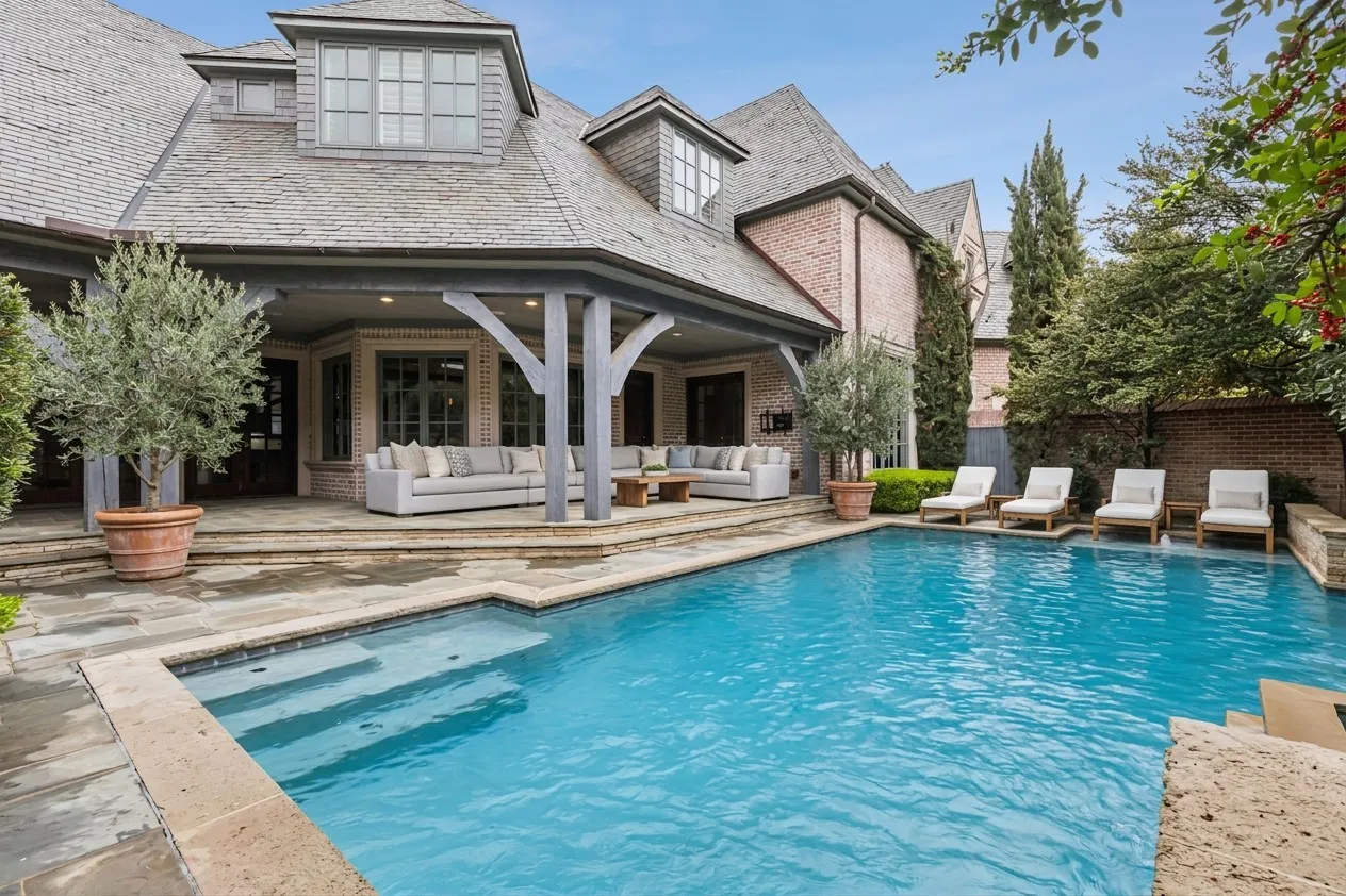 Built-in swimming pool with integrated steps, surrounded by stone coping and a stone patio