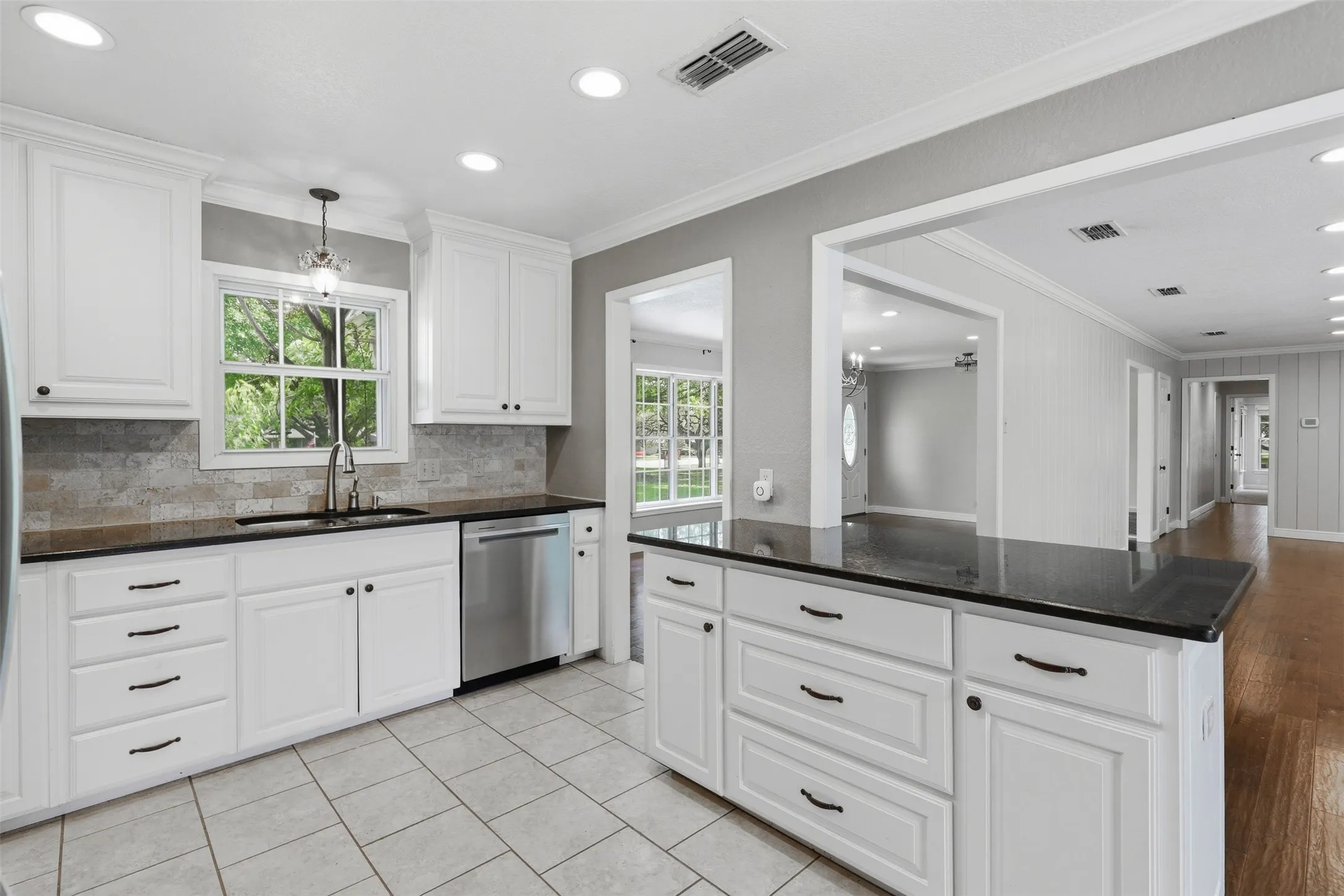 Kitchen featuring white cabinetry, dark countertops, stainless steel appliances, and tile flooring