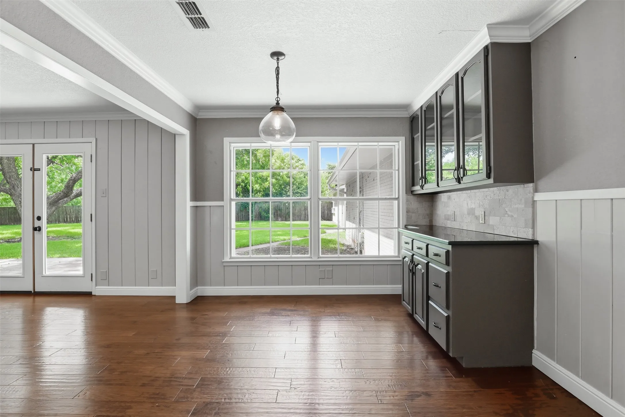 Spacious interior featuring wood-finish flooring, light gray board and batten wall paneling, and crown molding