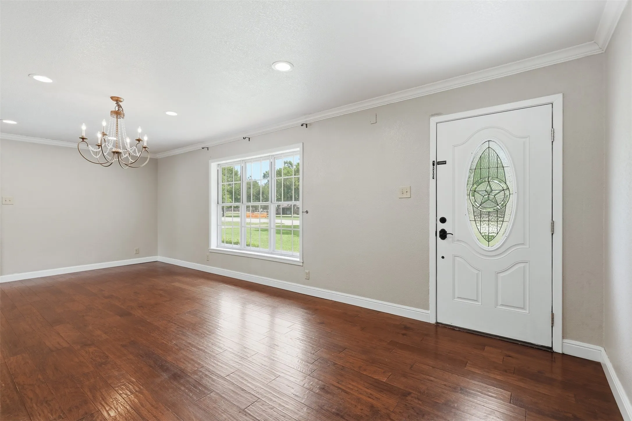 Entry area featuring wood-finish flooring, a white front door with decorative glass, and a multi-pane window