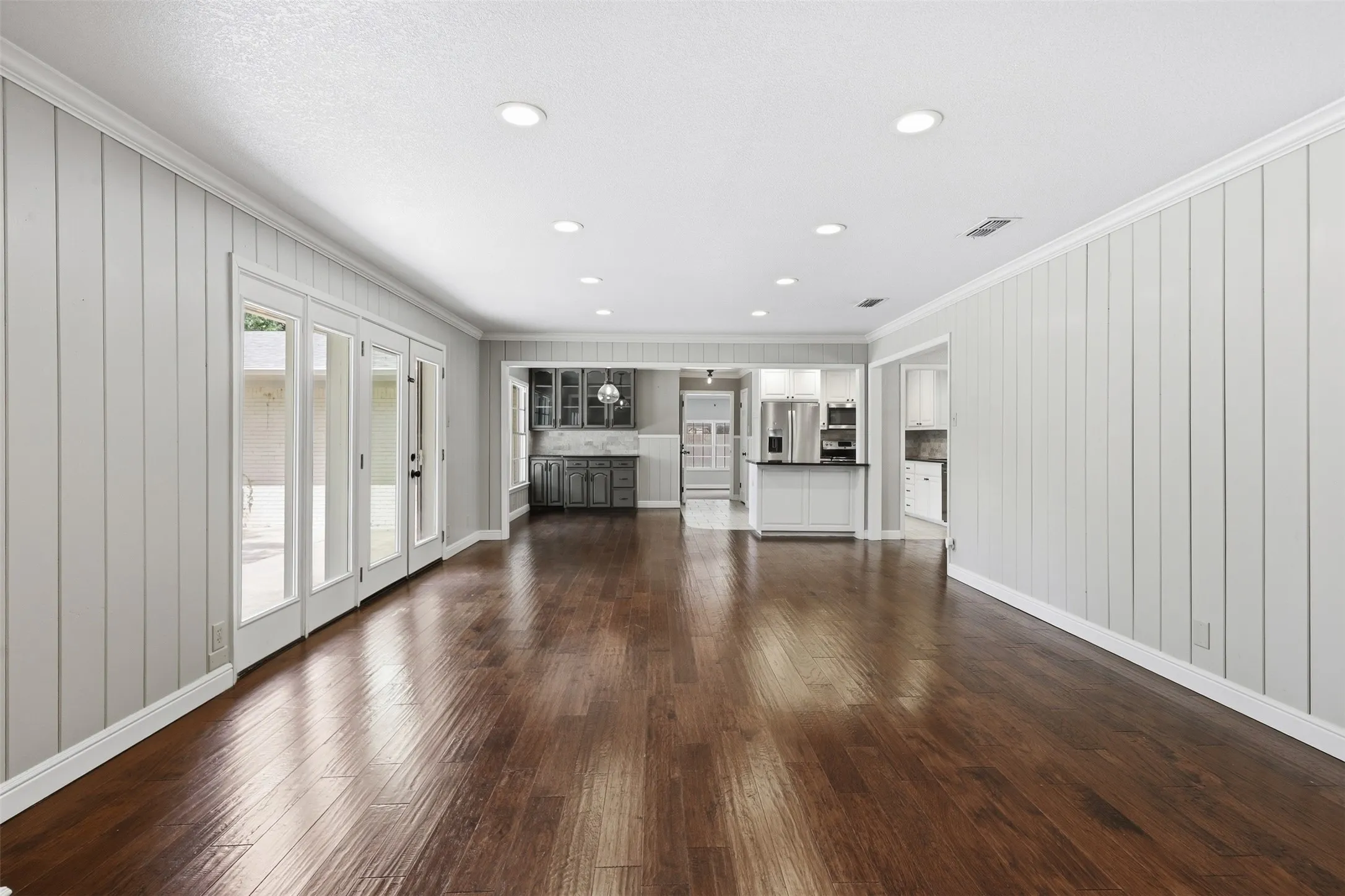 Expansive living area featuring rich wood-finish flooring and recessed lighting
