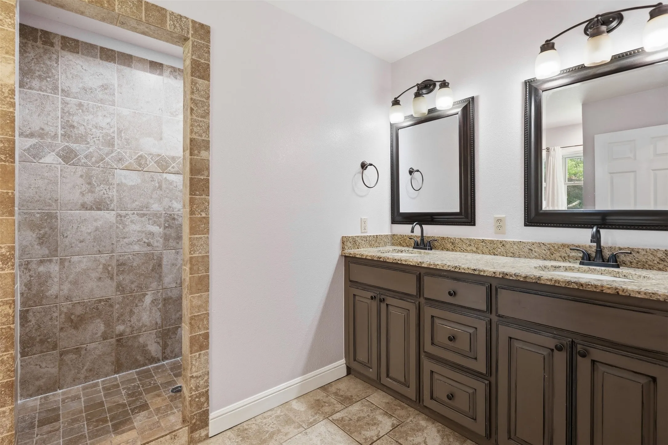 Dual vanity with granite countertops, undermount sinks, and dark wood-finish cabinetry
