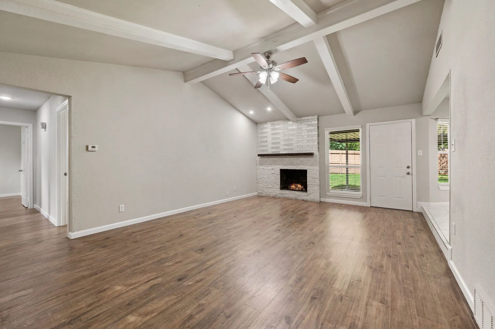 Vaulted ceiling with painted wood beams; Ceiling Fan; Stacked stone wood-burning Fireplace with mantel and designer tiles; Window Coverings are throughout