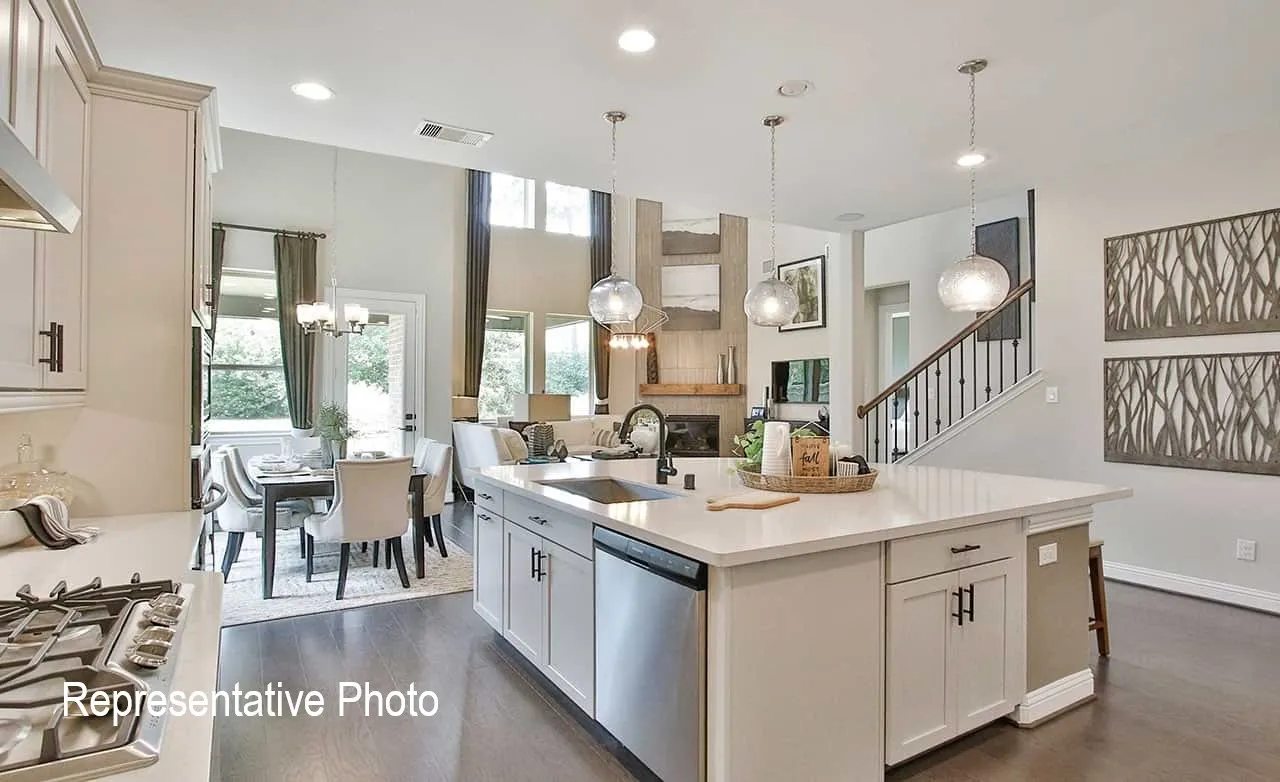 Open-concept kitchen featuring a large central island with seating, stainless steel appliances, pendant lighting, and wood-finish flooring throughout