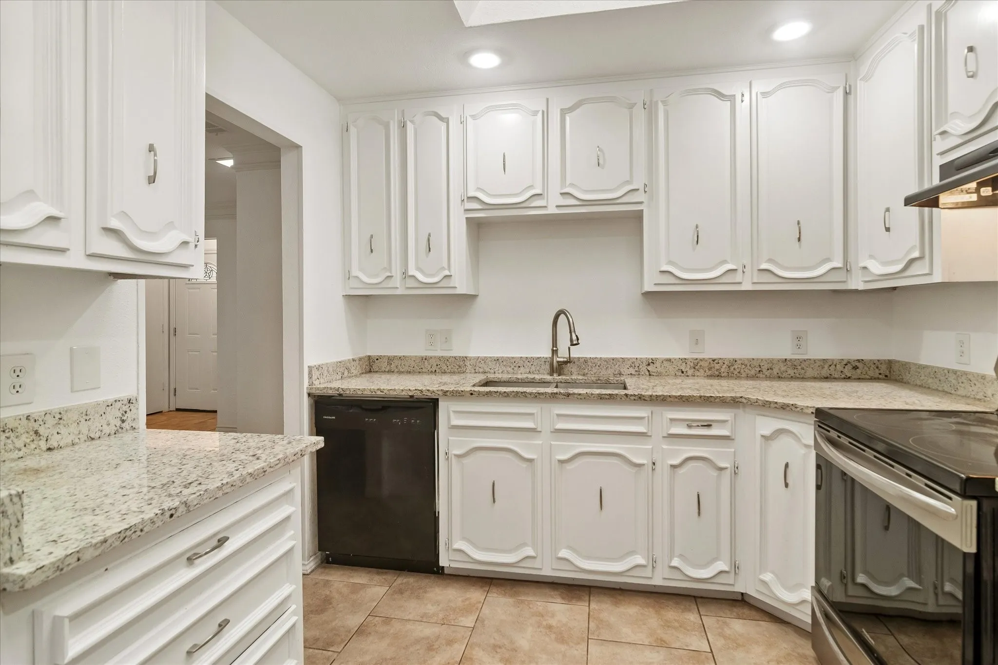 Kitchen featuring white cabinetry, speckled countertops, stainless steel sink with gooseneck faucet, black dishwasher, and tile flooring