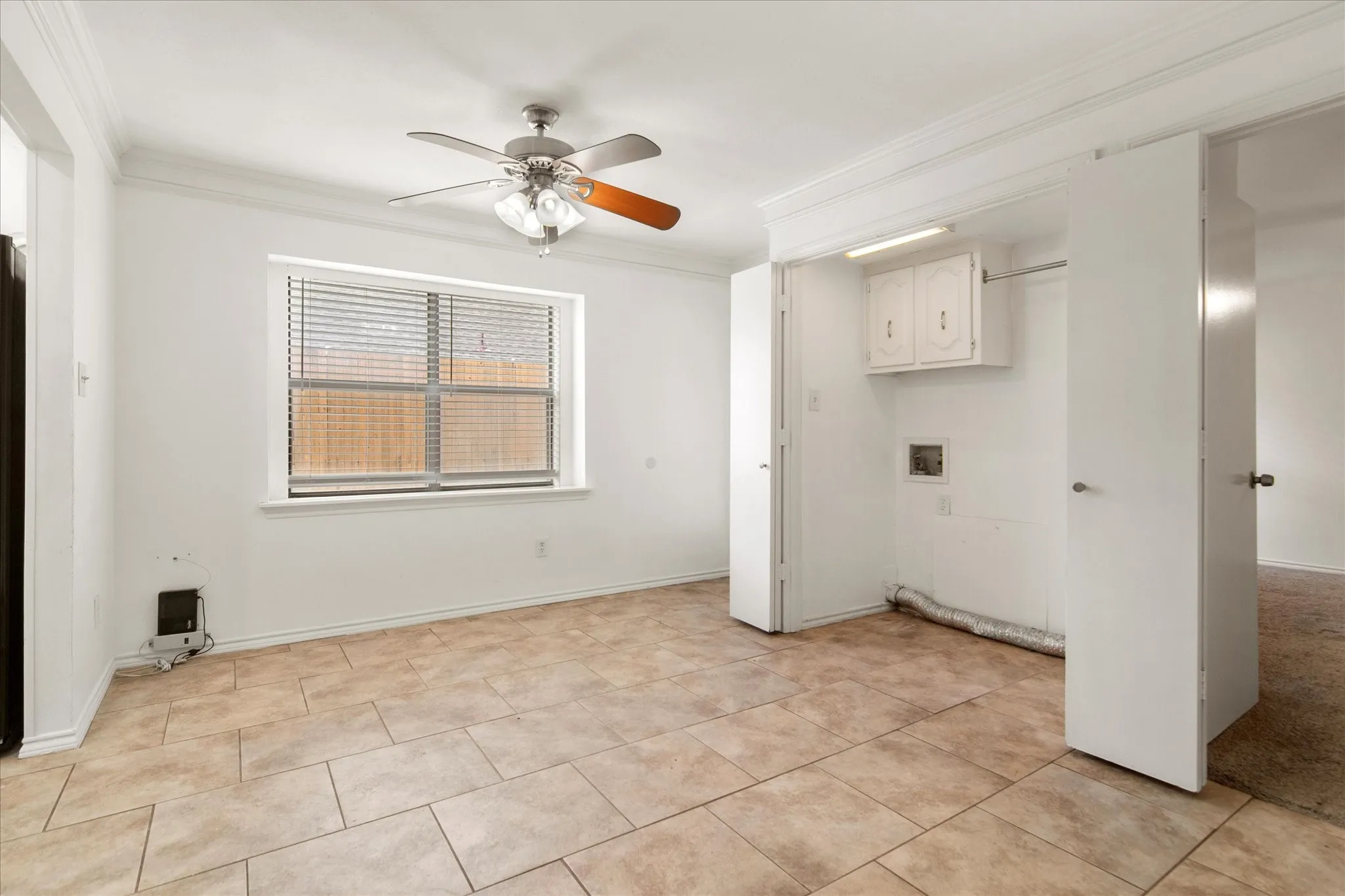 Spacious room featuring tile flooring, a ceiling fan with light fixture, and a window with blinds