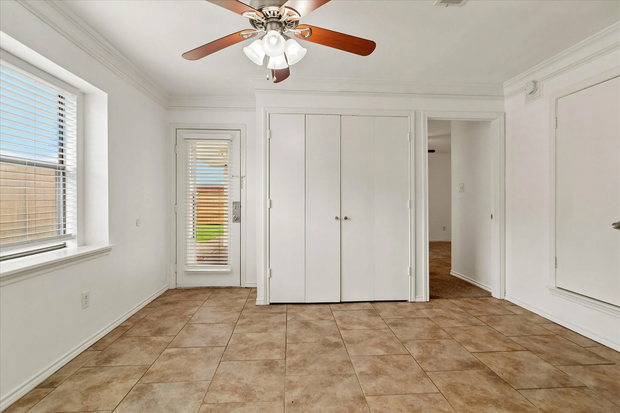 Room featuring ceramic tile flooring, a ceiling fan with integrated lighting, and crown molding