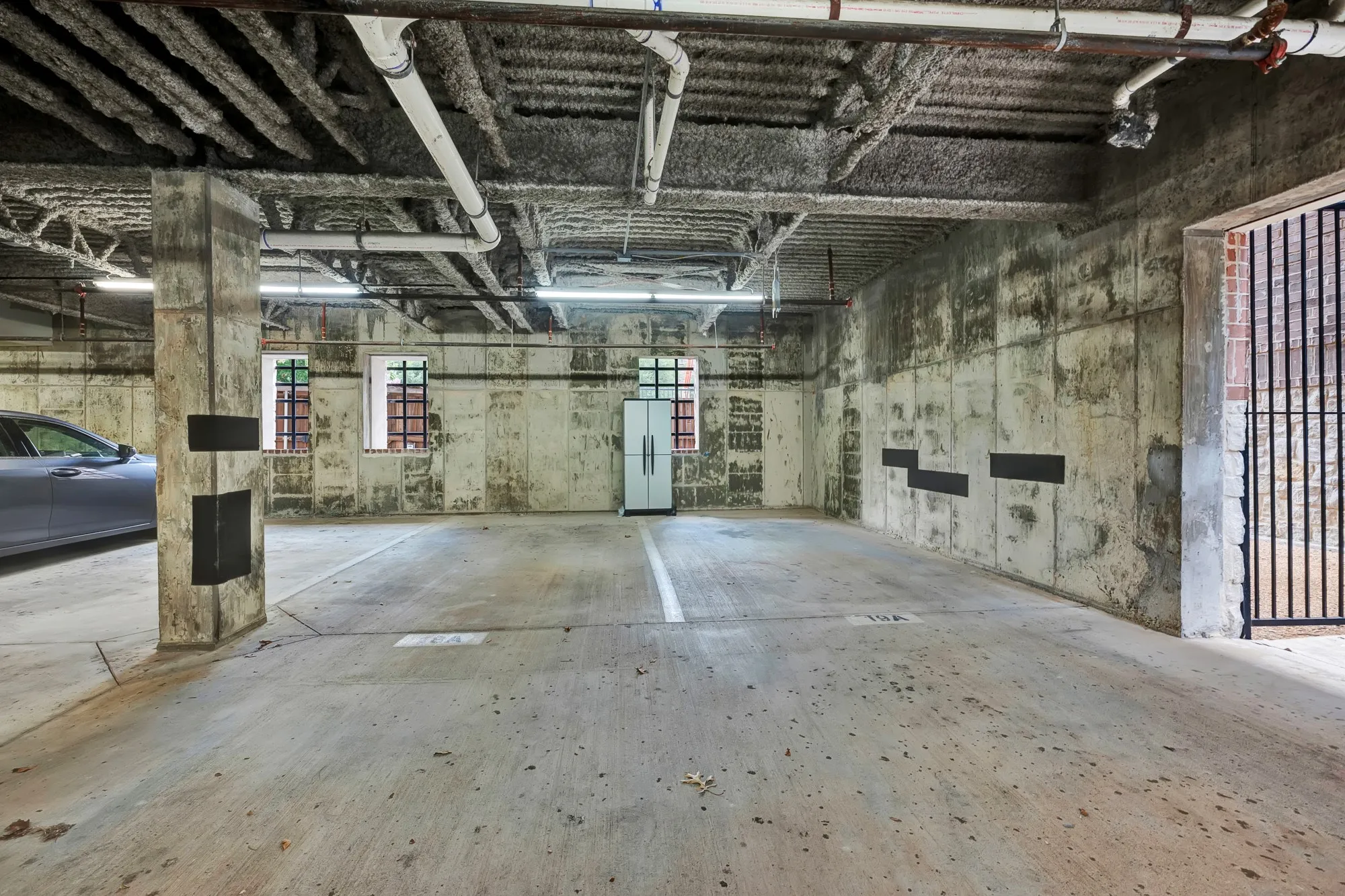 Dedicated underground parking garage featuring a concrete floor and exposed concrete walls