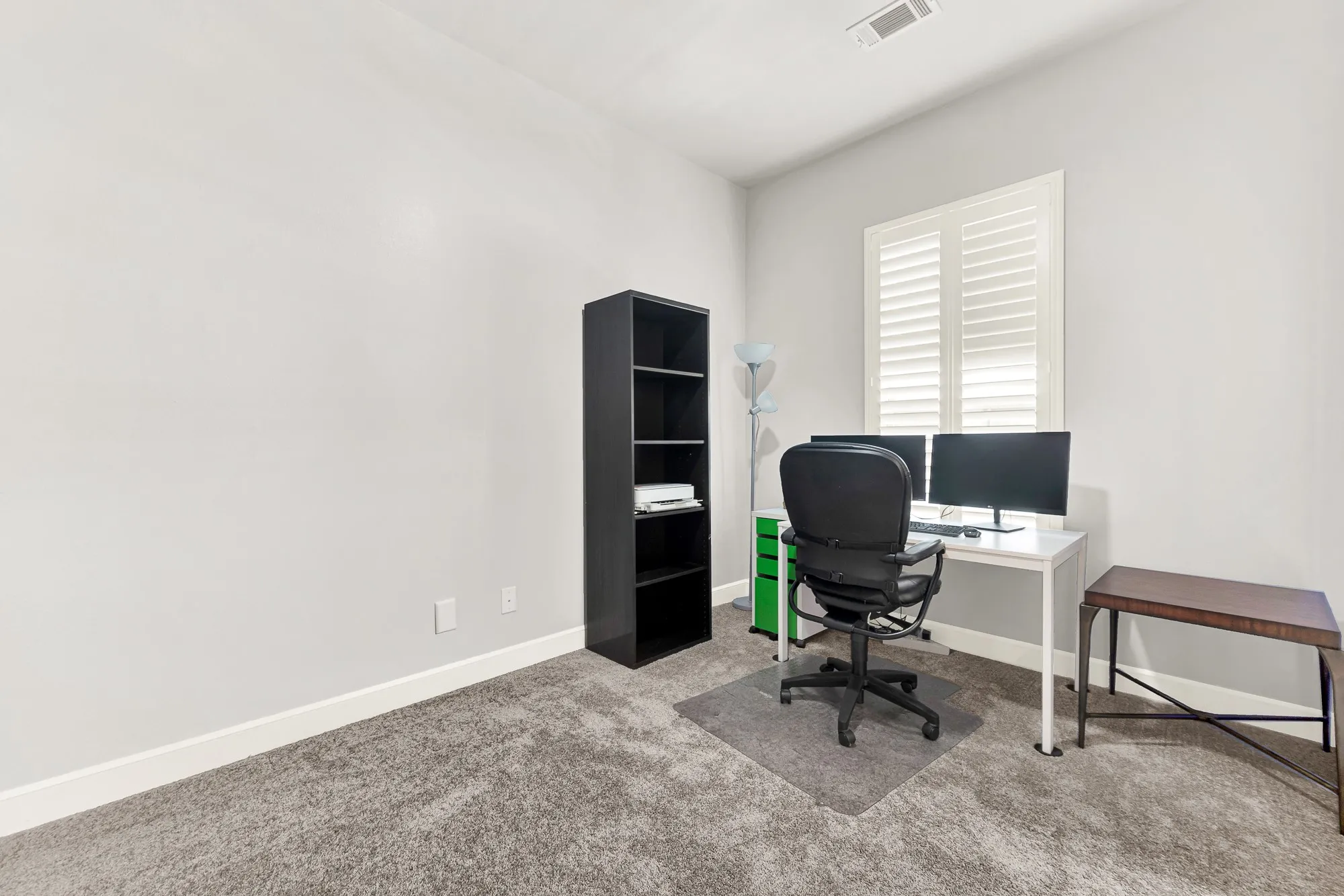 Bedroom featuring a window with plantation shutters, a recessed ceiling vent, and a built-in shelving unit