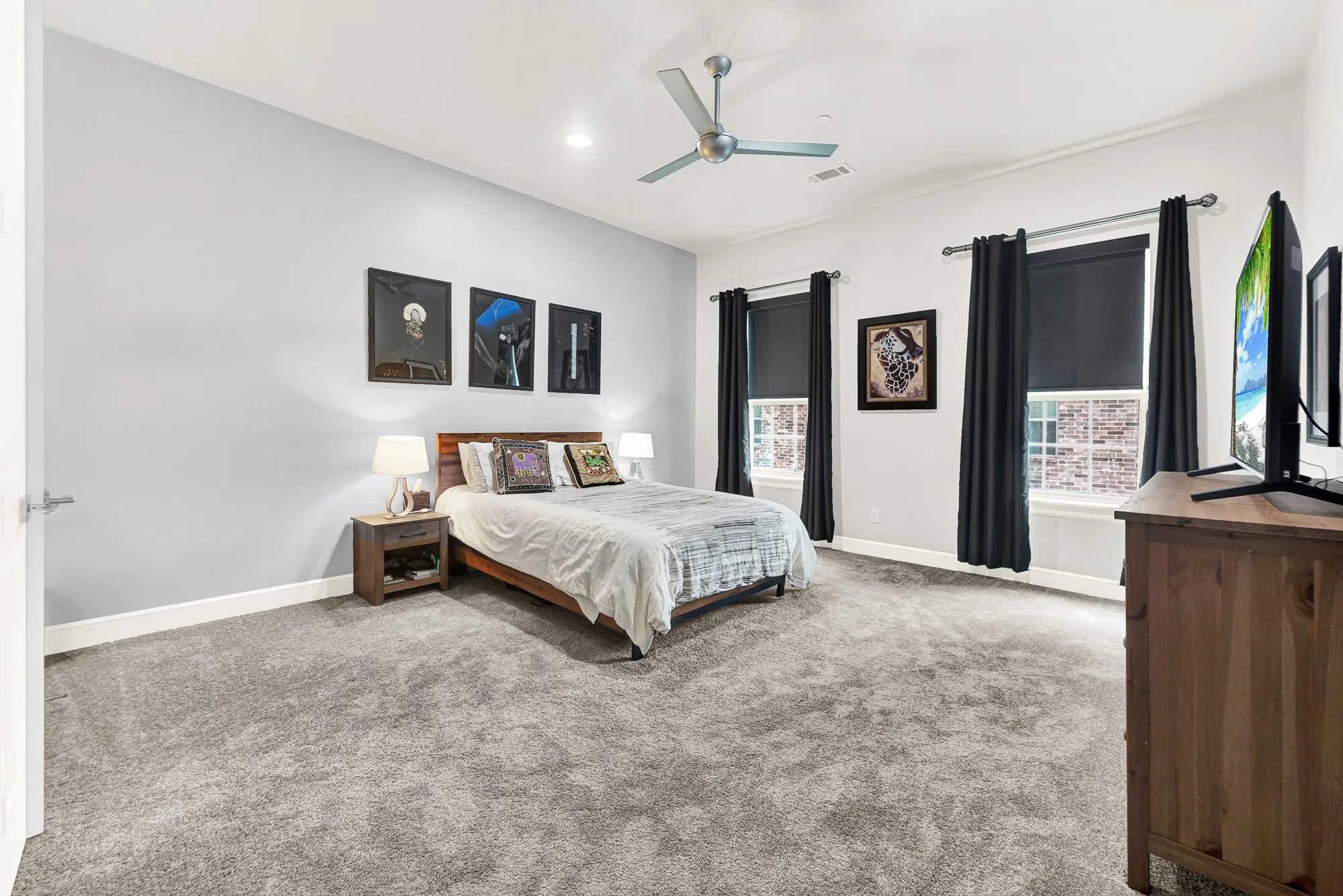 Expansive bedroom featuring light gray walls, plush gray carpeting, and crown molding