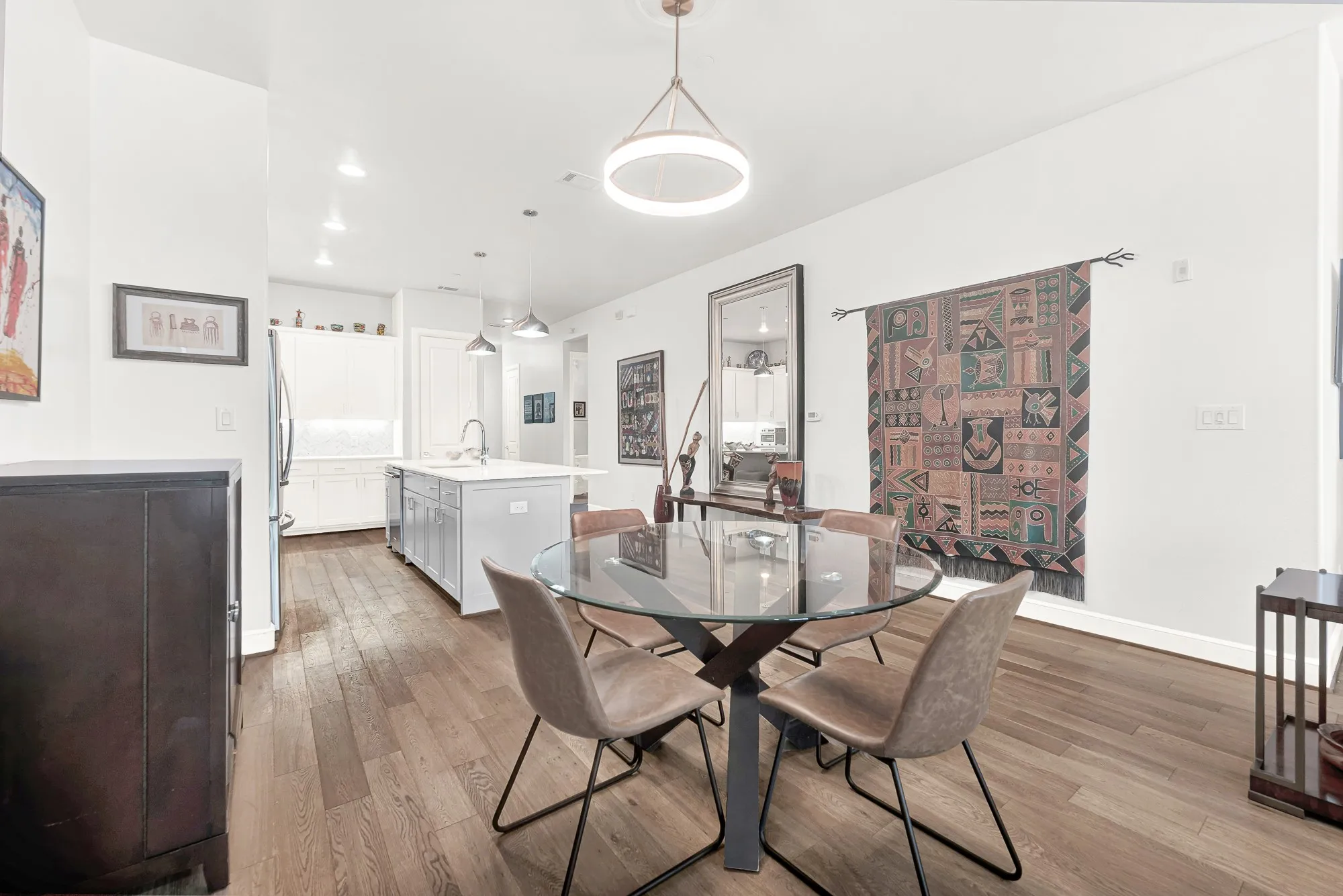 Open-concept dining area with wood-finish flooring, recessed lighting, and a modern circular chandelier