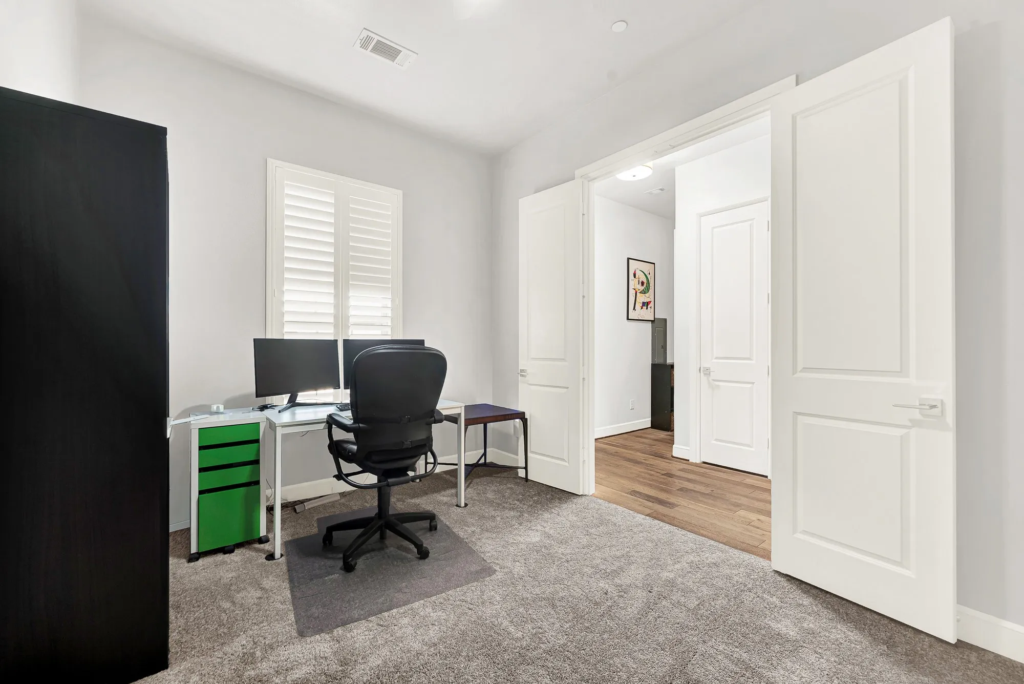 Carpeted room, perfect for a home office with a double door entry and a window featuring white plantation shutters