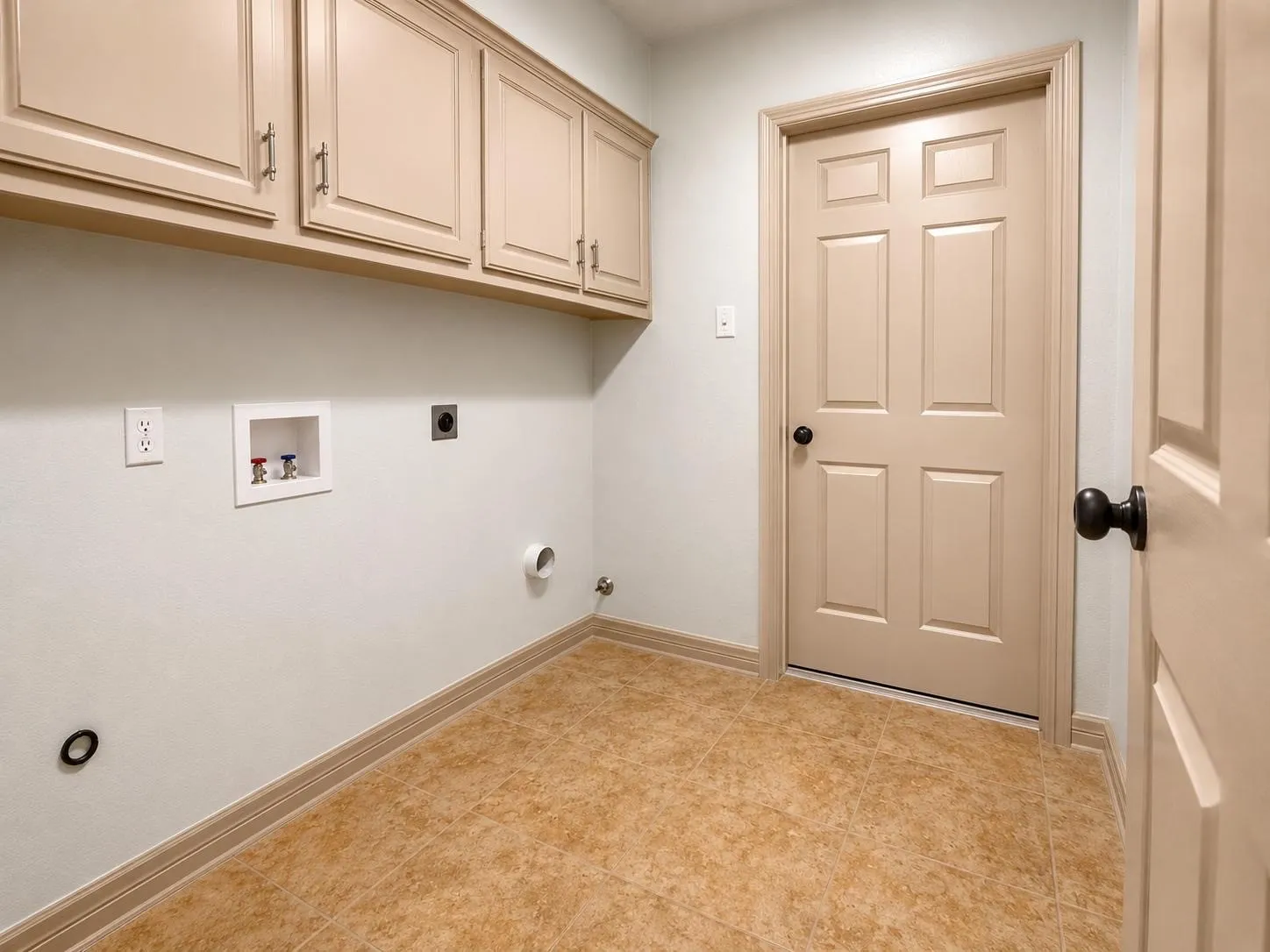 Laundry area featuring neutral-toned cabinetry, tile flooring, and a paneled door