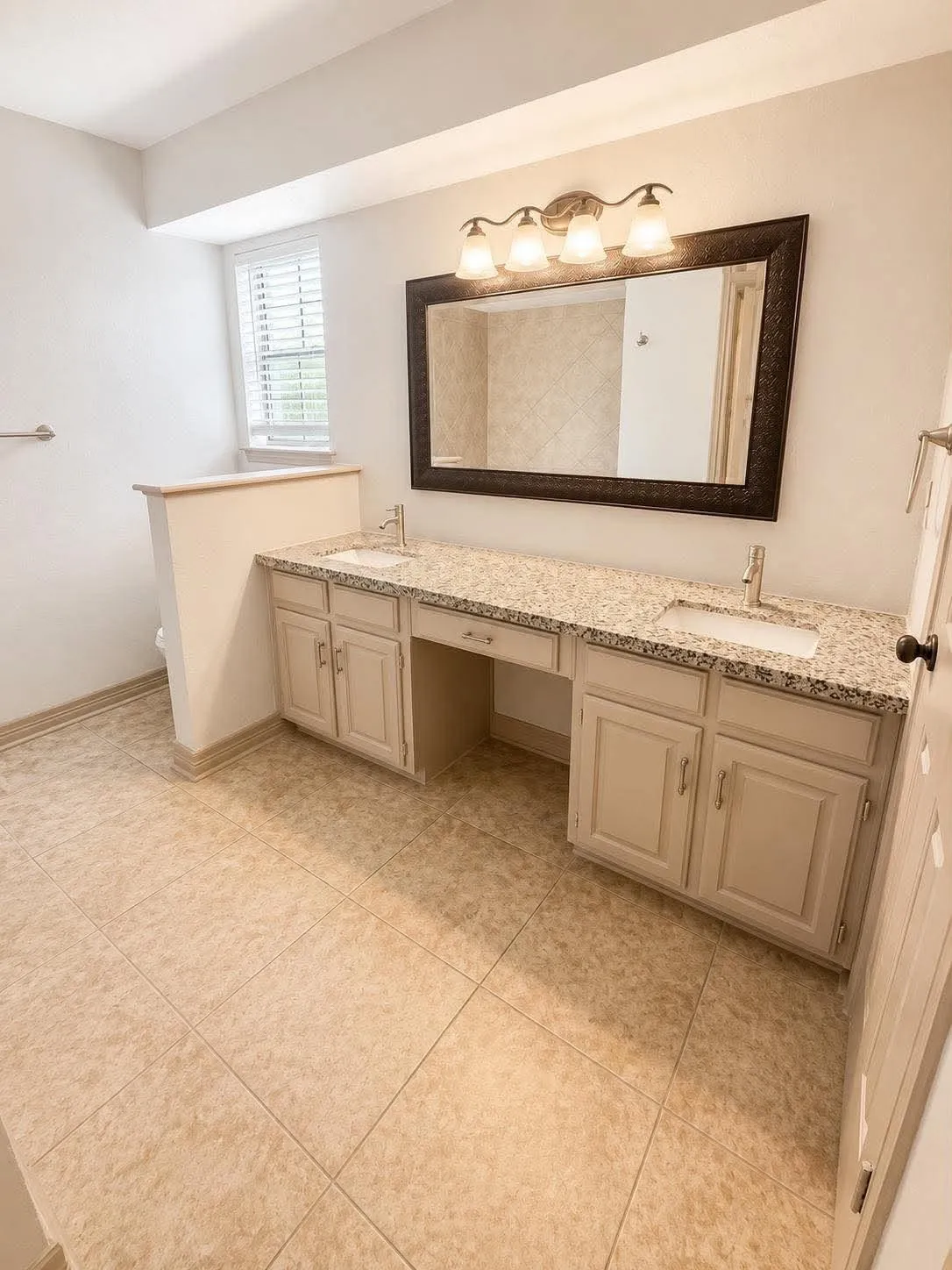 Bathroom featuring an expansive dual vanity with integrated sinks, granite-finish countertop, and light-toned cabinetry