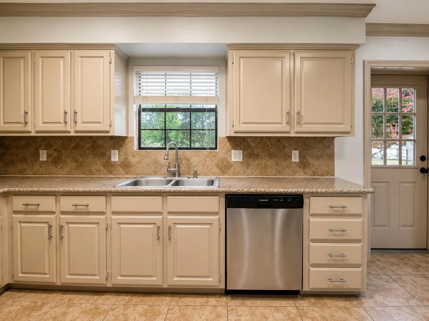 Kitchen featuring light-toned cabinetry, a stainless steel double basin sink, and a stainless steel dishwasher