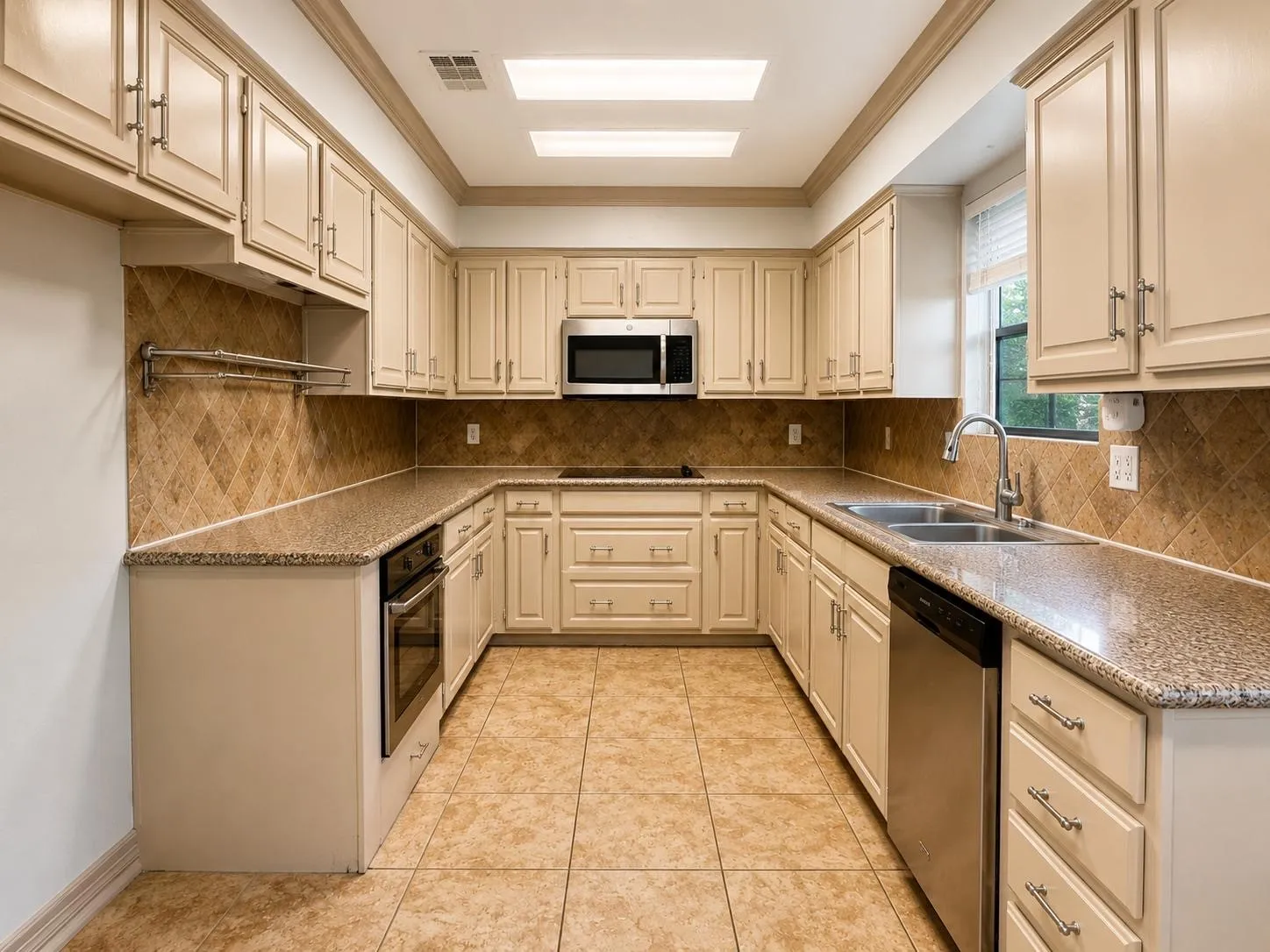 Kitchen featuring extensive cream cabinetry, granite countertops, and a tiled backsplash
