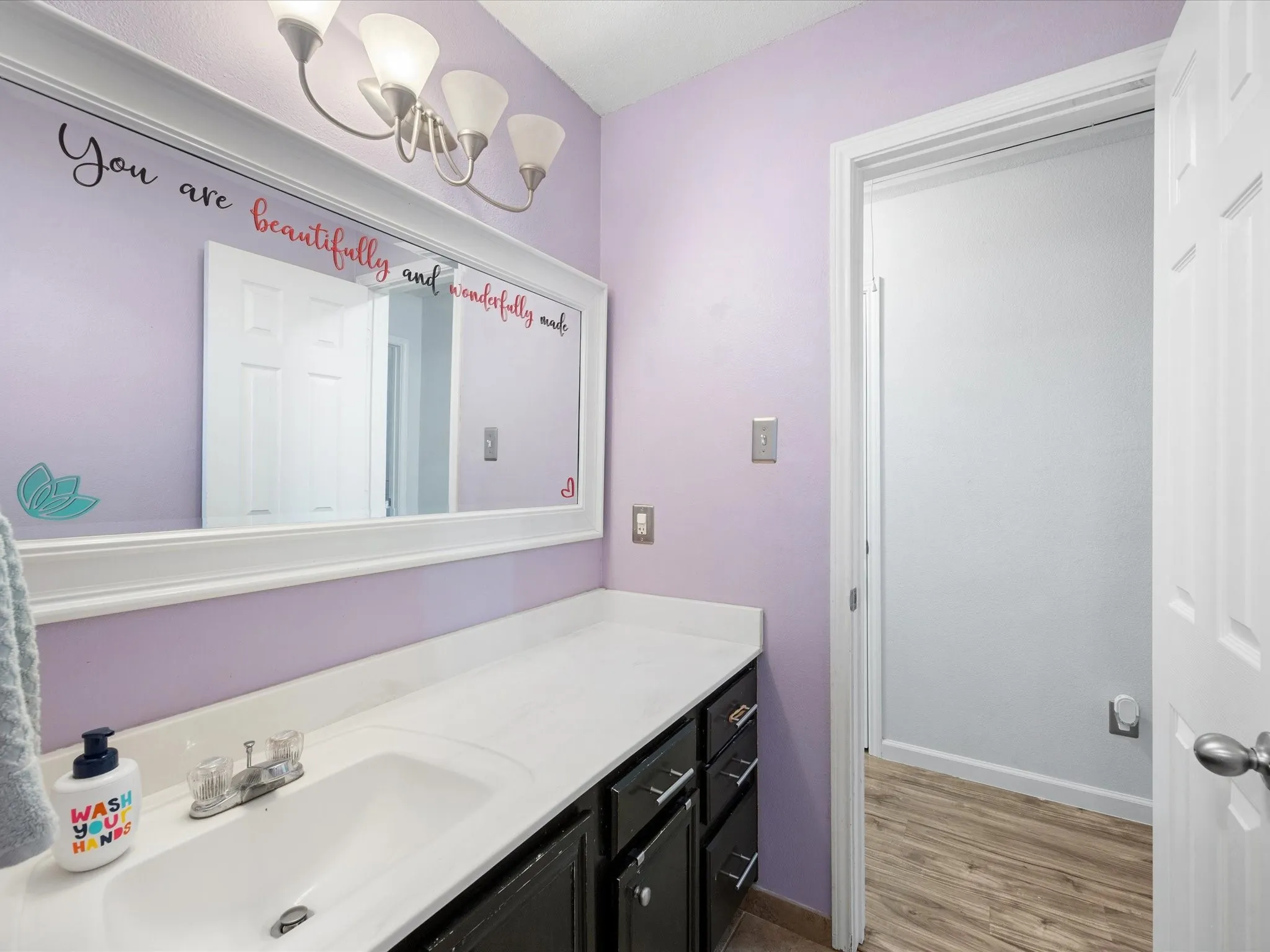 Bathroom featuring a long single vanity with an integrated sink, a white countertop, and dark cabinetry