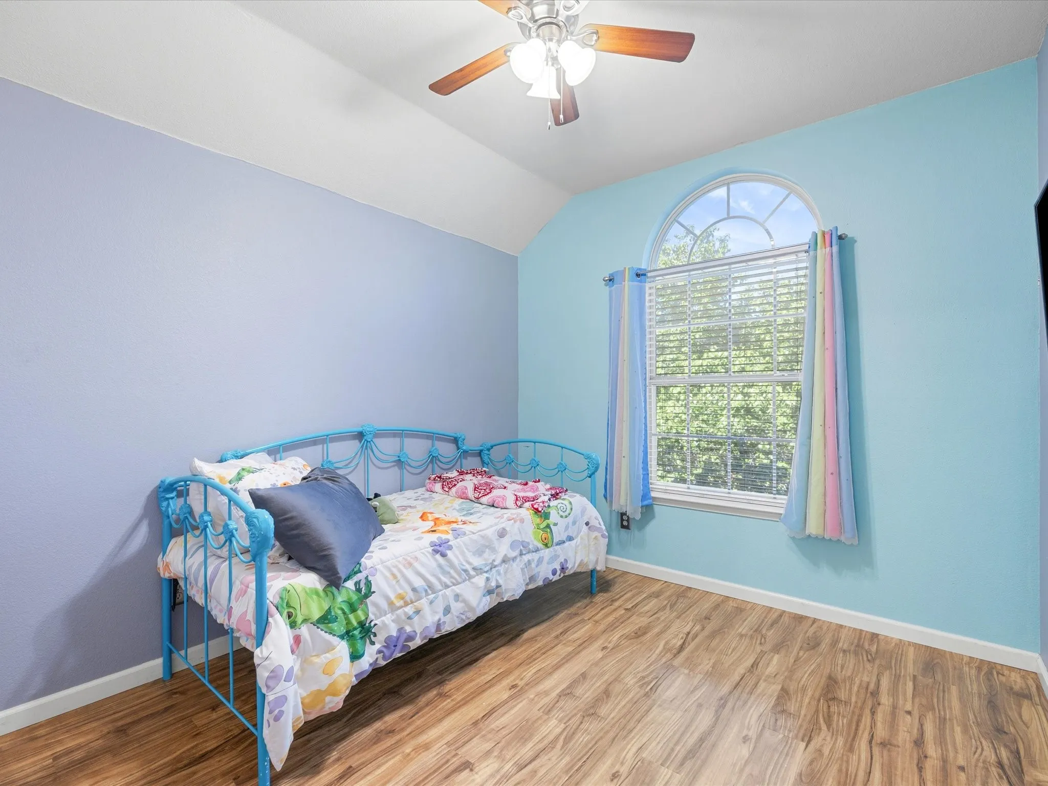 Bedroom featuring wood-finish flooring, a vaulted ceiling, and a ceiling fan with light fixture
