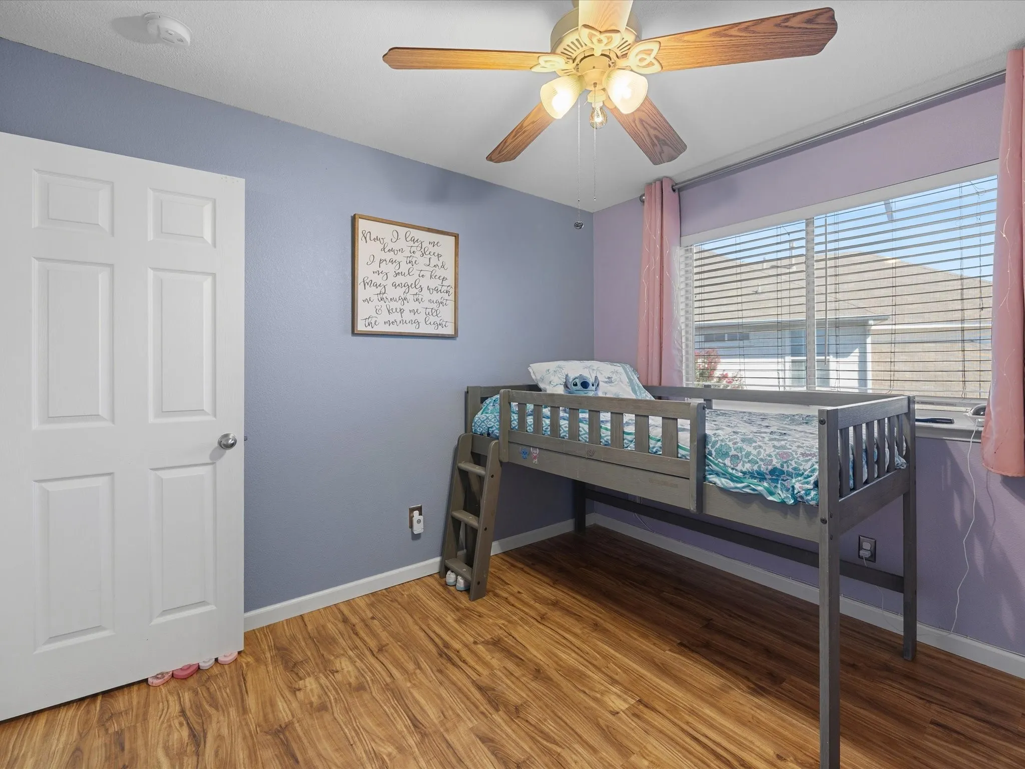 Room with wood-finish flooring, a ceiling fan, and a paneled white door