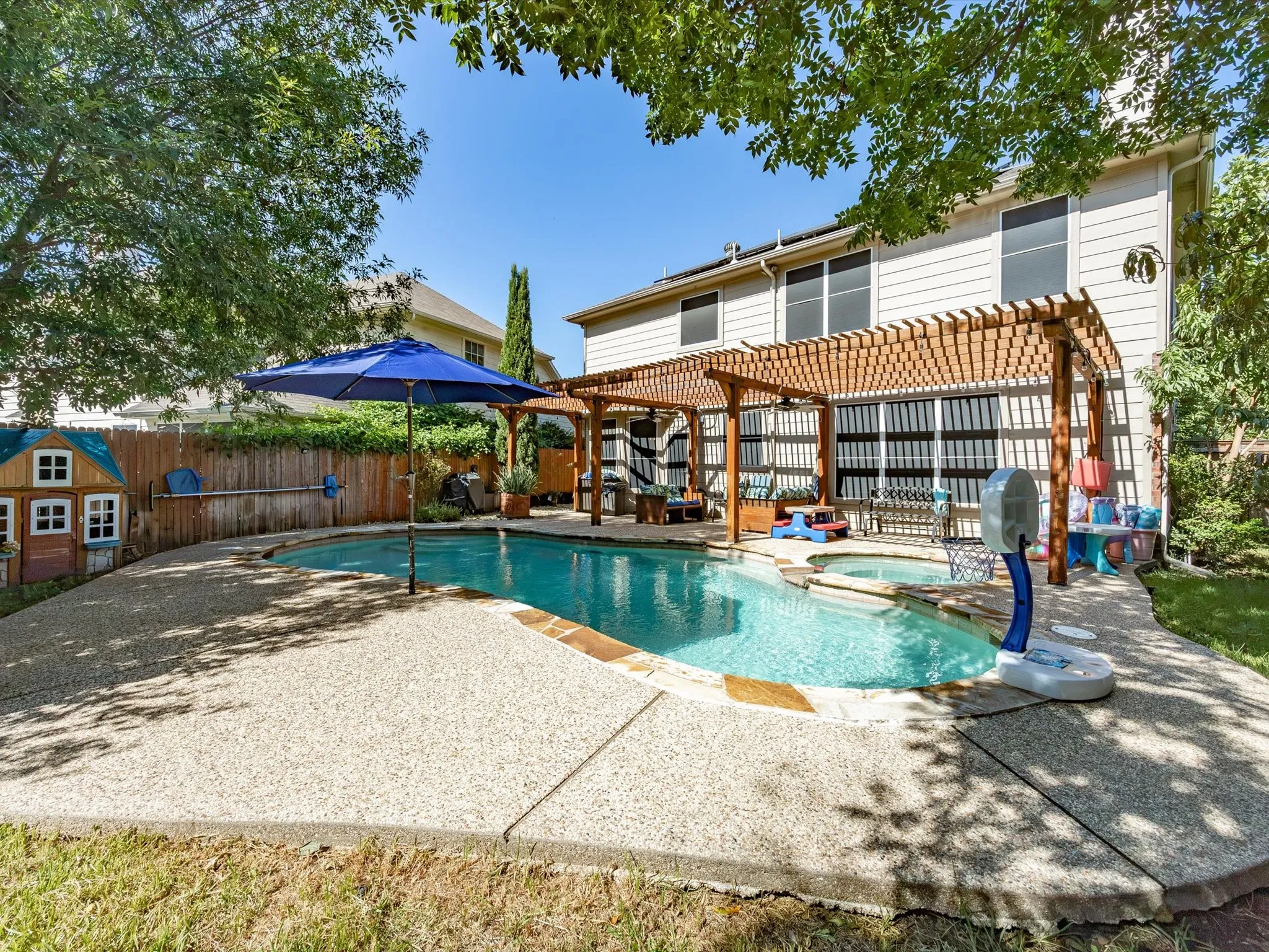 Backyard oasis featuring a freeform swimming pool, integrated spa, and expansive exposed aggregate patio