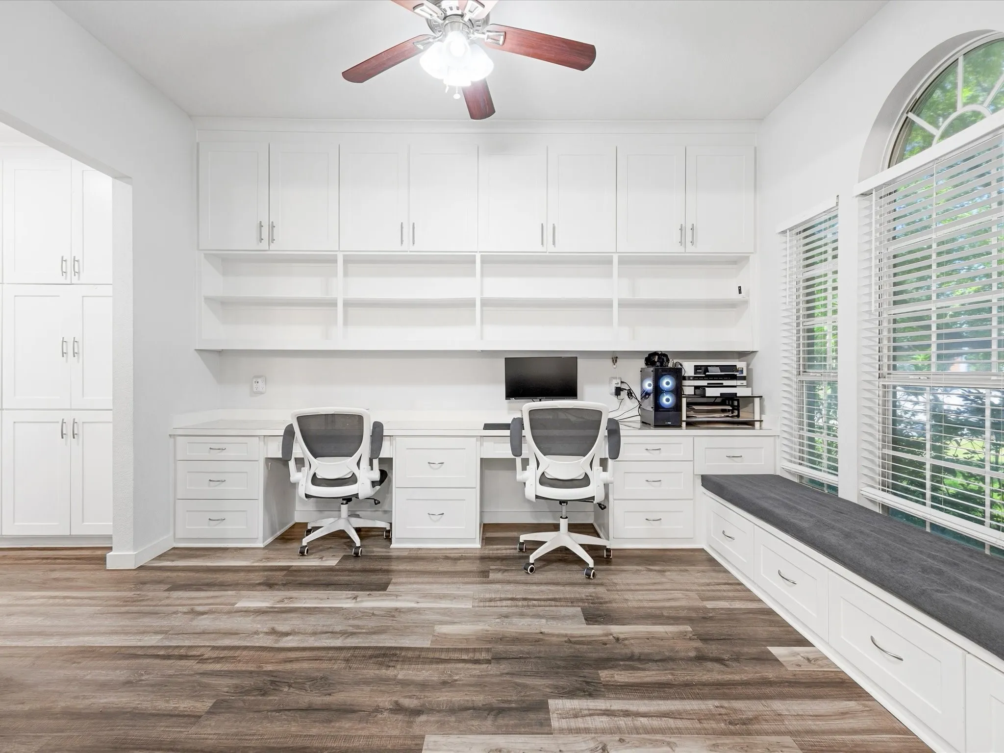 Dedicated workspace featuring extensive built-in white cabinetry, integrated shelving, and dual desk areas