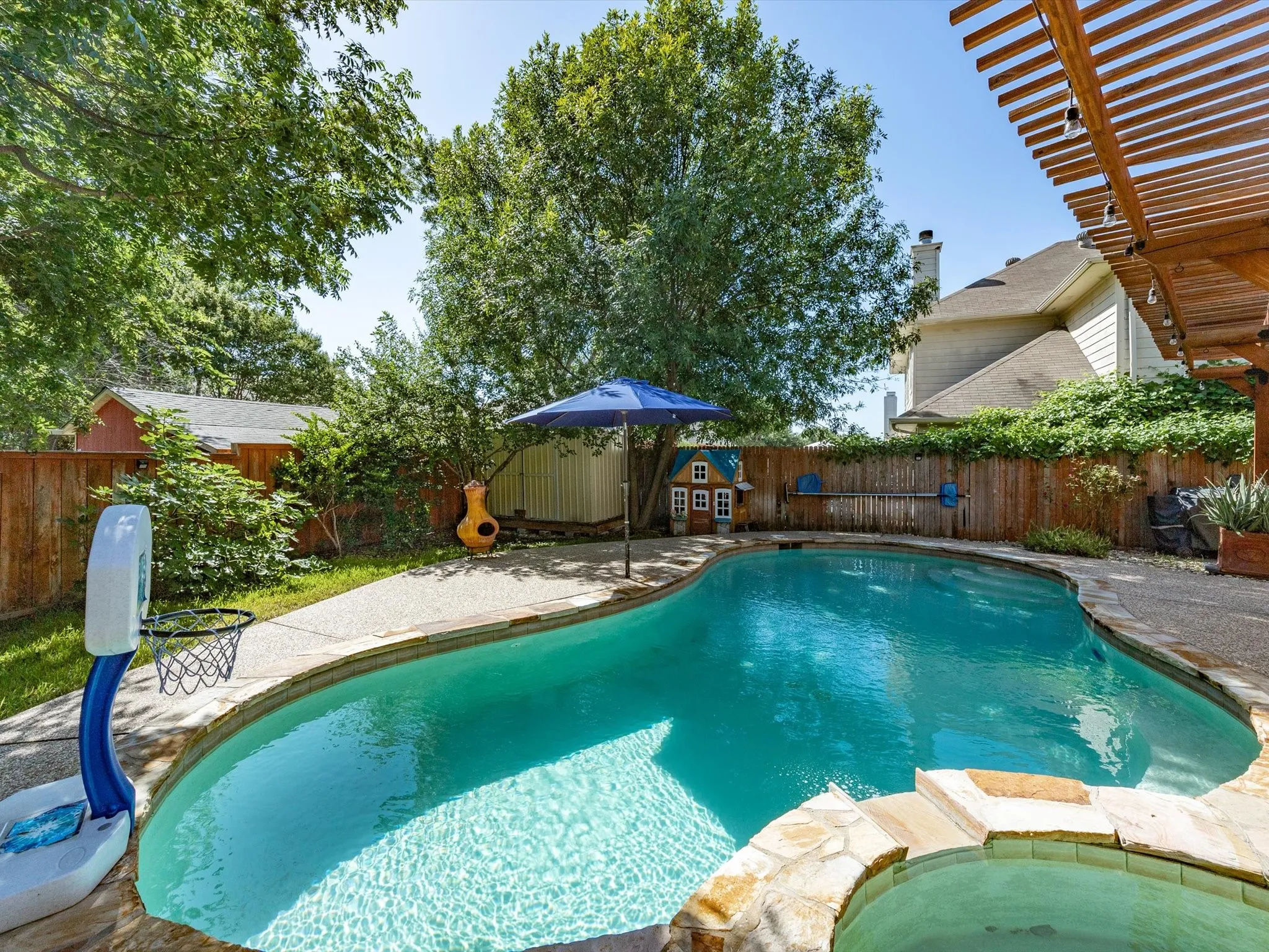 Curved swimming pool with stone coping and an integrated spa