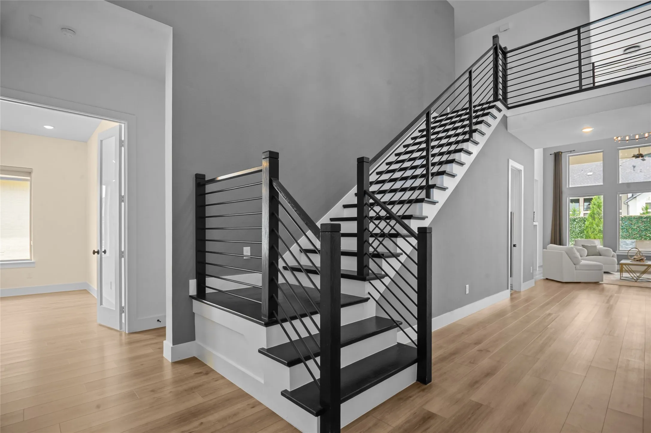 Staircase featuring black metal railings and treads, white risers, and wood-finish flooring