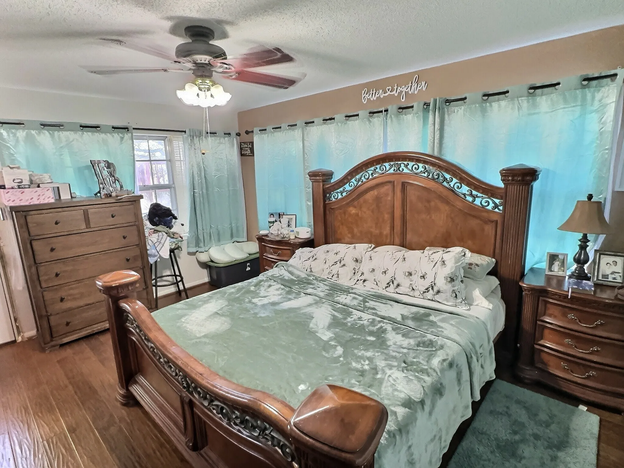 Hardwood flooring complements a neutral wall color, enhanced by a ceiling fan with integrated lighting
