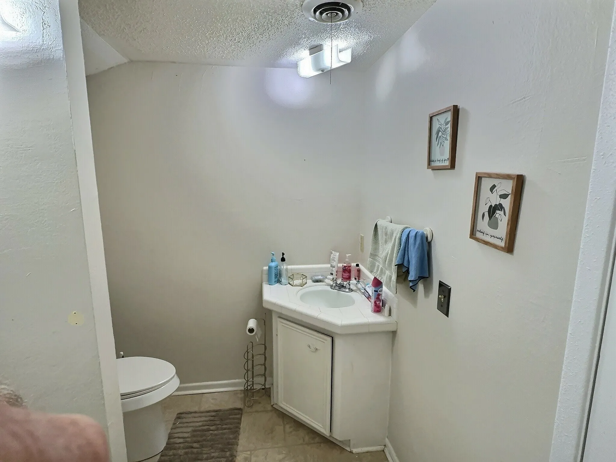 Powder room featuring a corner vanity with an integrated sink, a built-in cabinet, and tiled flooring