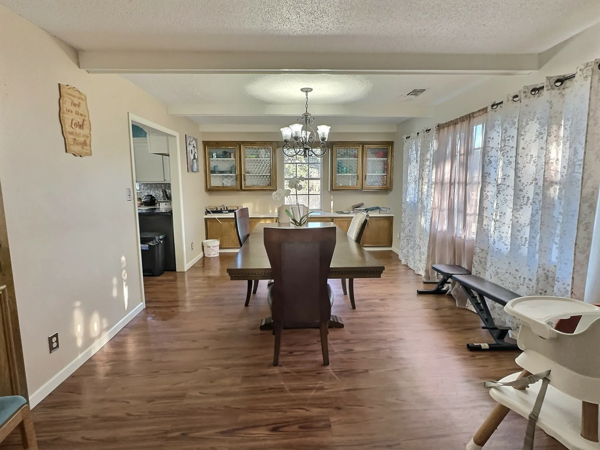 Dining area featuring wood-finish flooring, a contemporary chandelier, and built-in cabinetry with glass-front uppers
