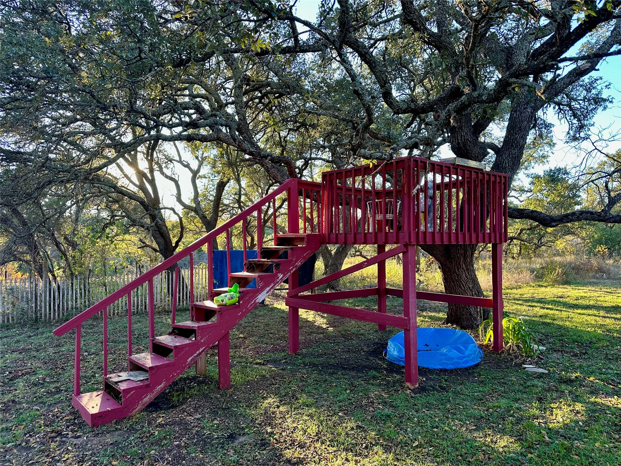 Tree-mounted wooden play structure featuring a raised platform, integrated staircase, and protective railing