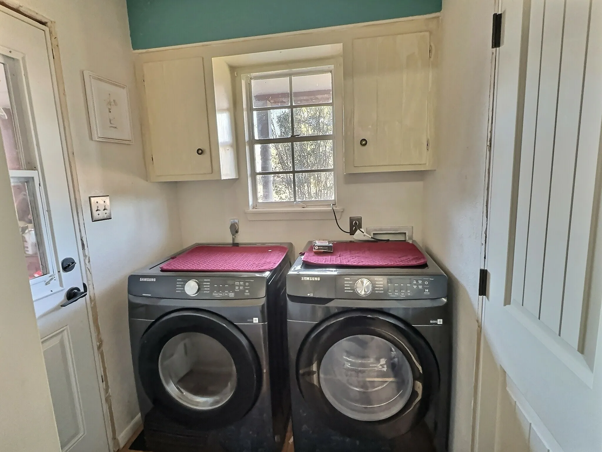 Laundry area featuring a window, overhead cabinetry, and a paneled door