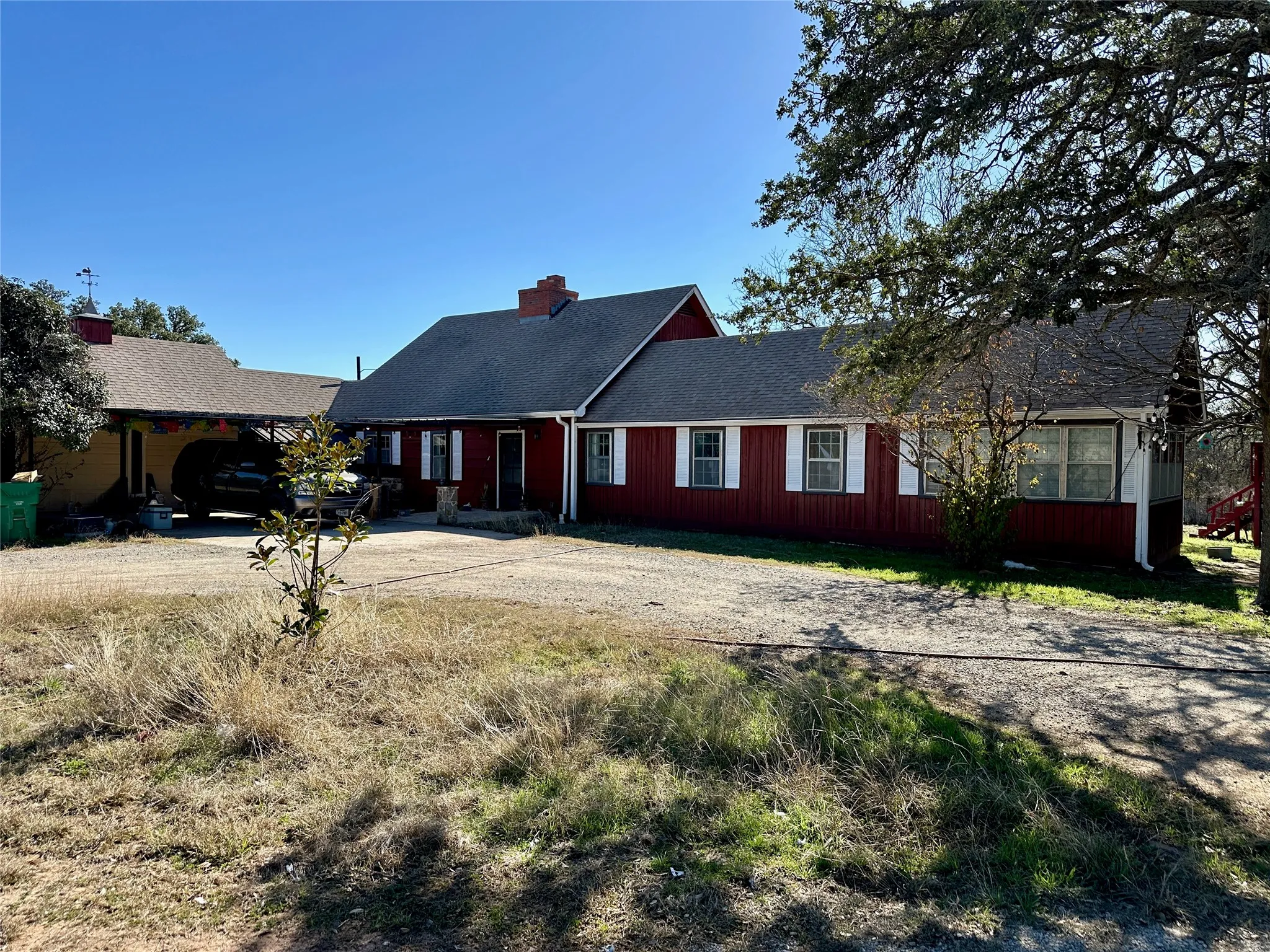 Red siding exterior with white window shutters and a dark shingle roof