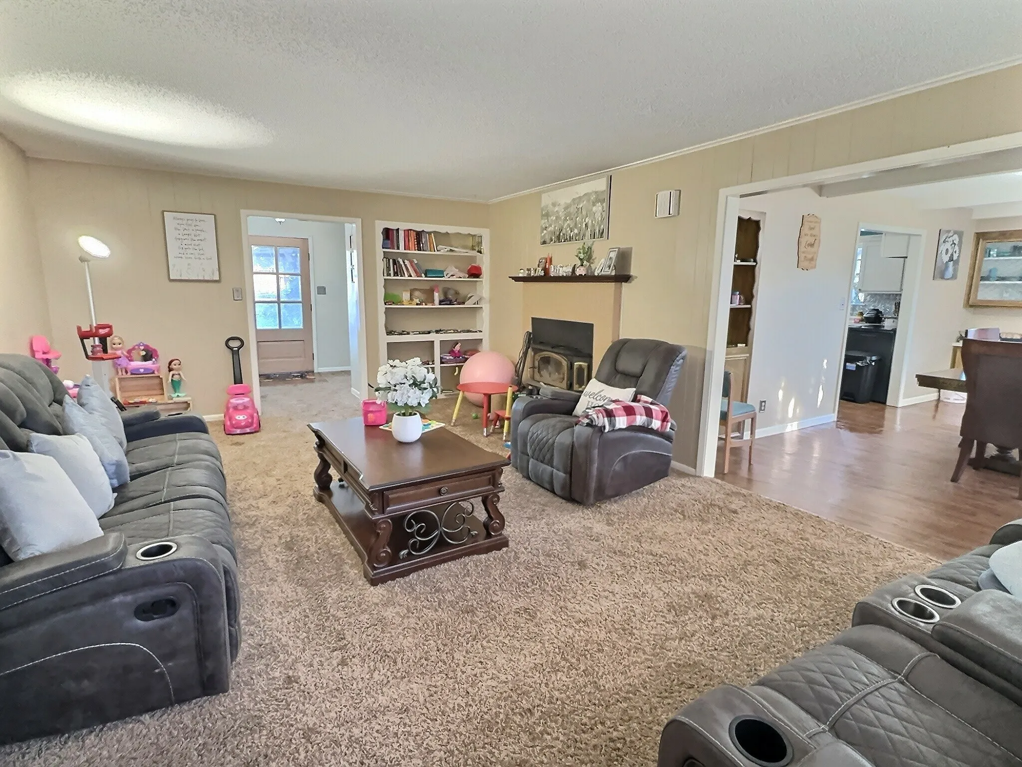 Spacious living area featuring neutral carpeting and a built-in fireplace