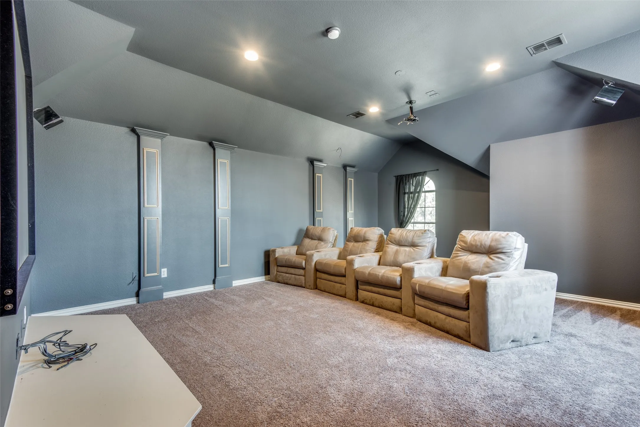 Dedicated entertainment space featuring a large projection screen, recessed lighting, and sloped ceilings