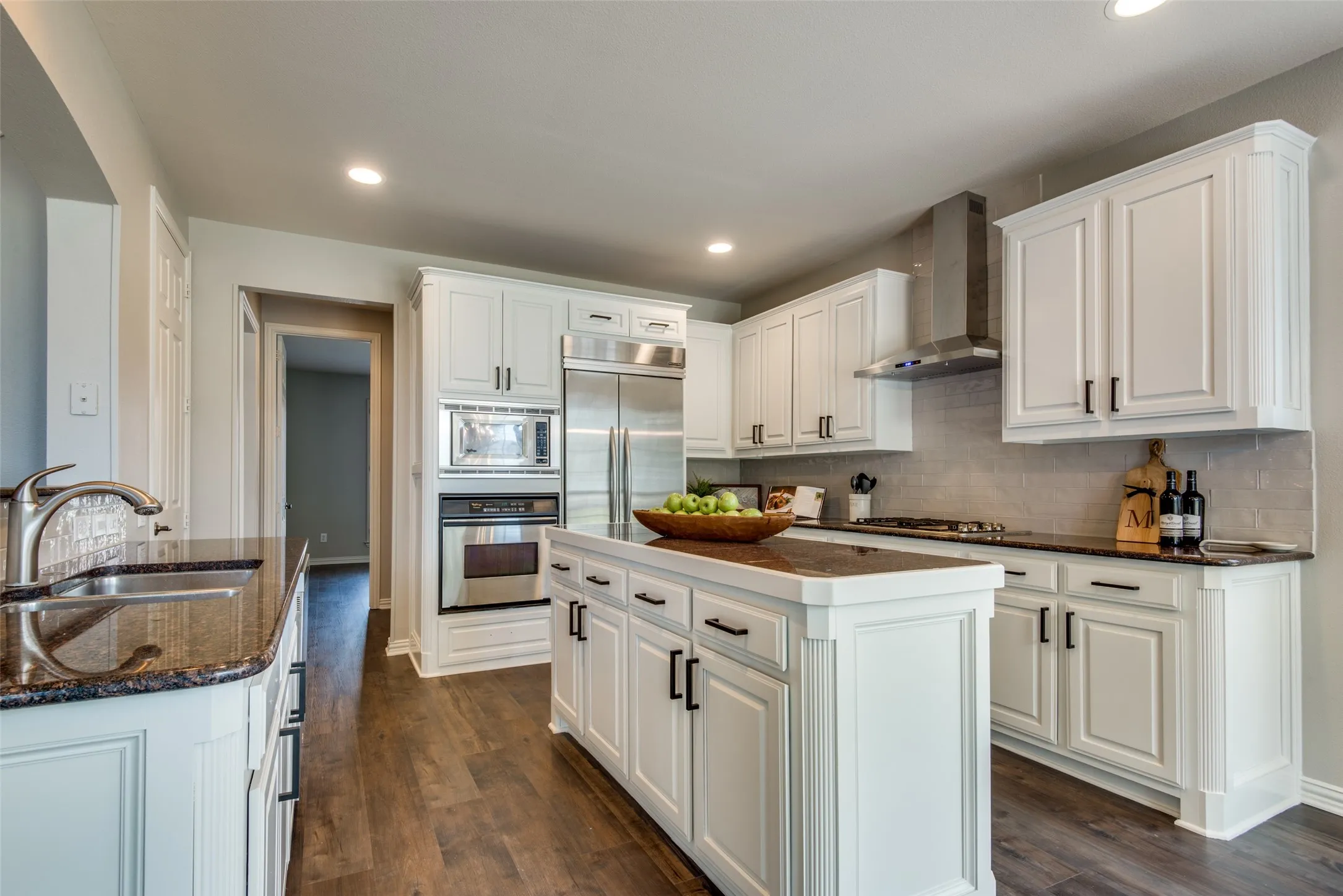 Modern kitchen featuring white cabinetry, dark wood-finish flooring, a central island, stainless steel appliances, and dark countertops