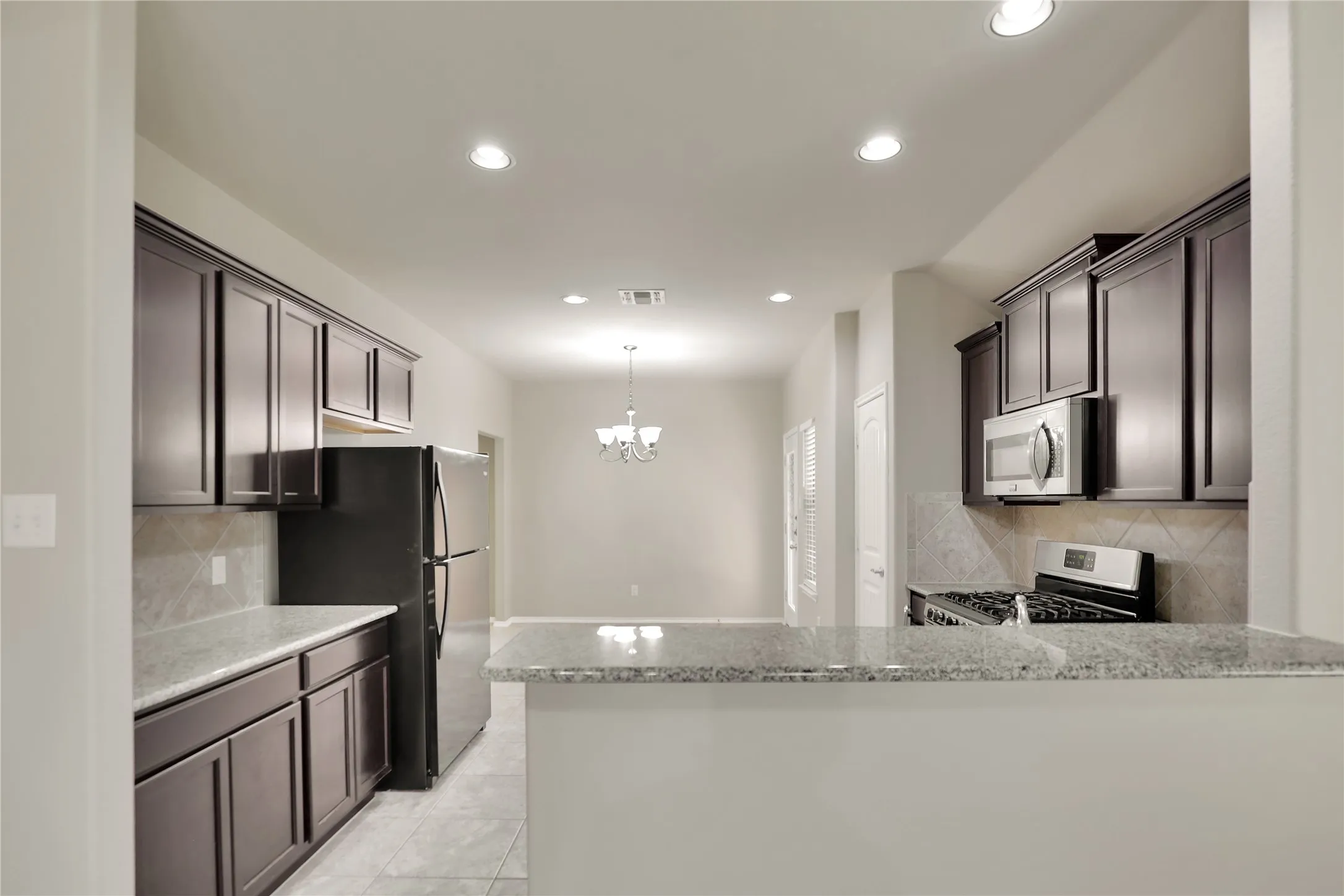 Kitchen featuring dark wood-finish cabinetry, light-toned countertops, and a full suite of appliances