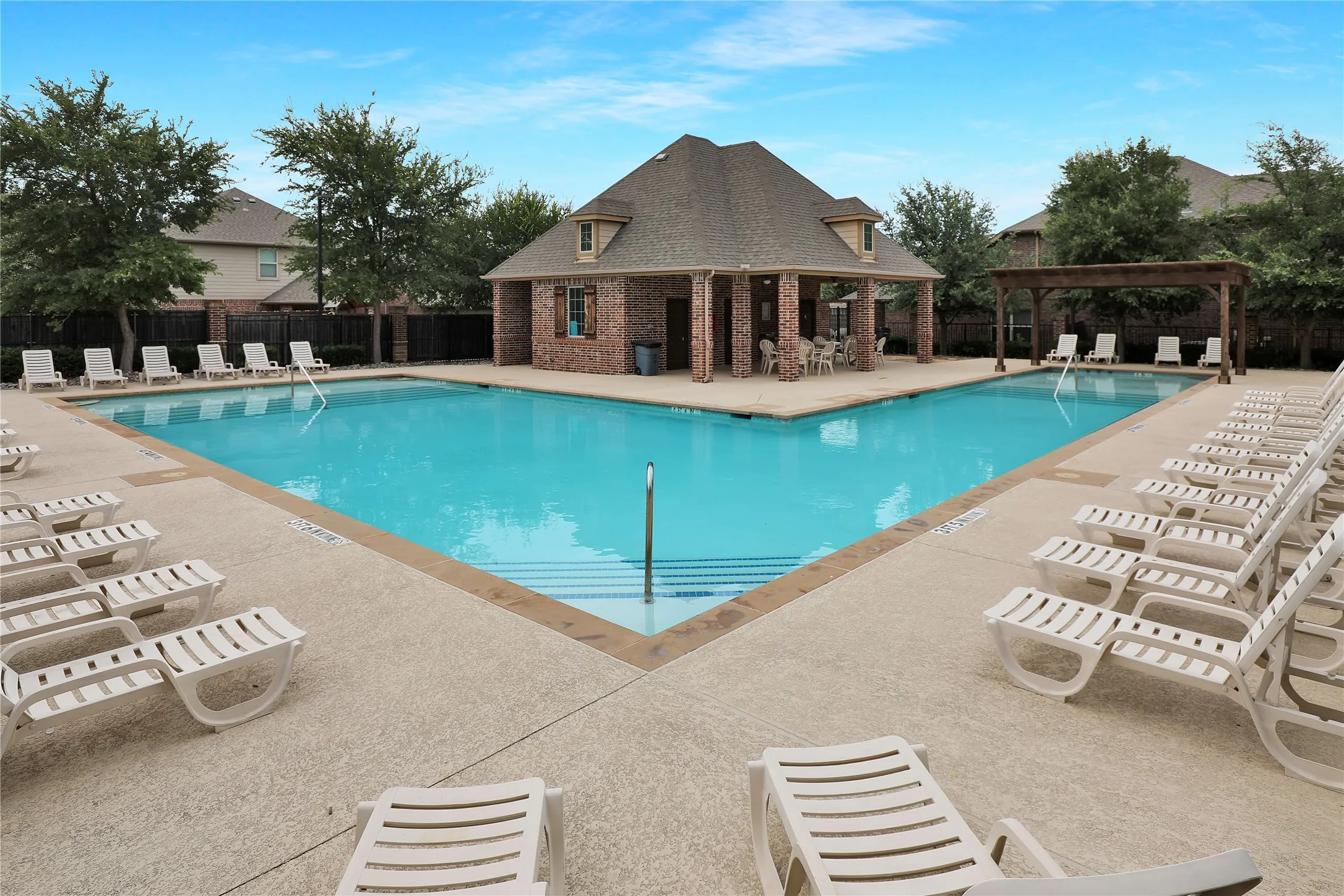 Expansive swimming pool with a surrounding concrete​​‌​​​​‌​​‌‌​‌‌​​​‌‌​‌​‌​‌​​​‌​​ deck