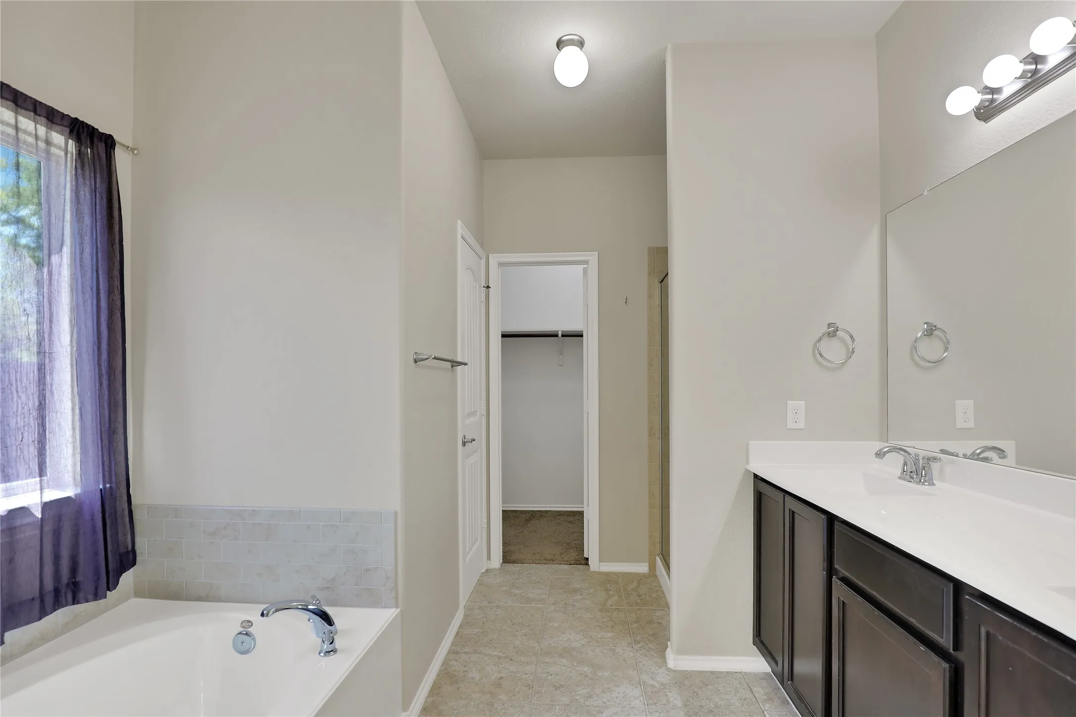 Bathroom with dual dark wood-finish vanity, integrated sink, and large mirror