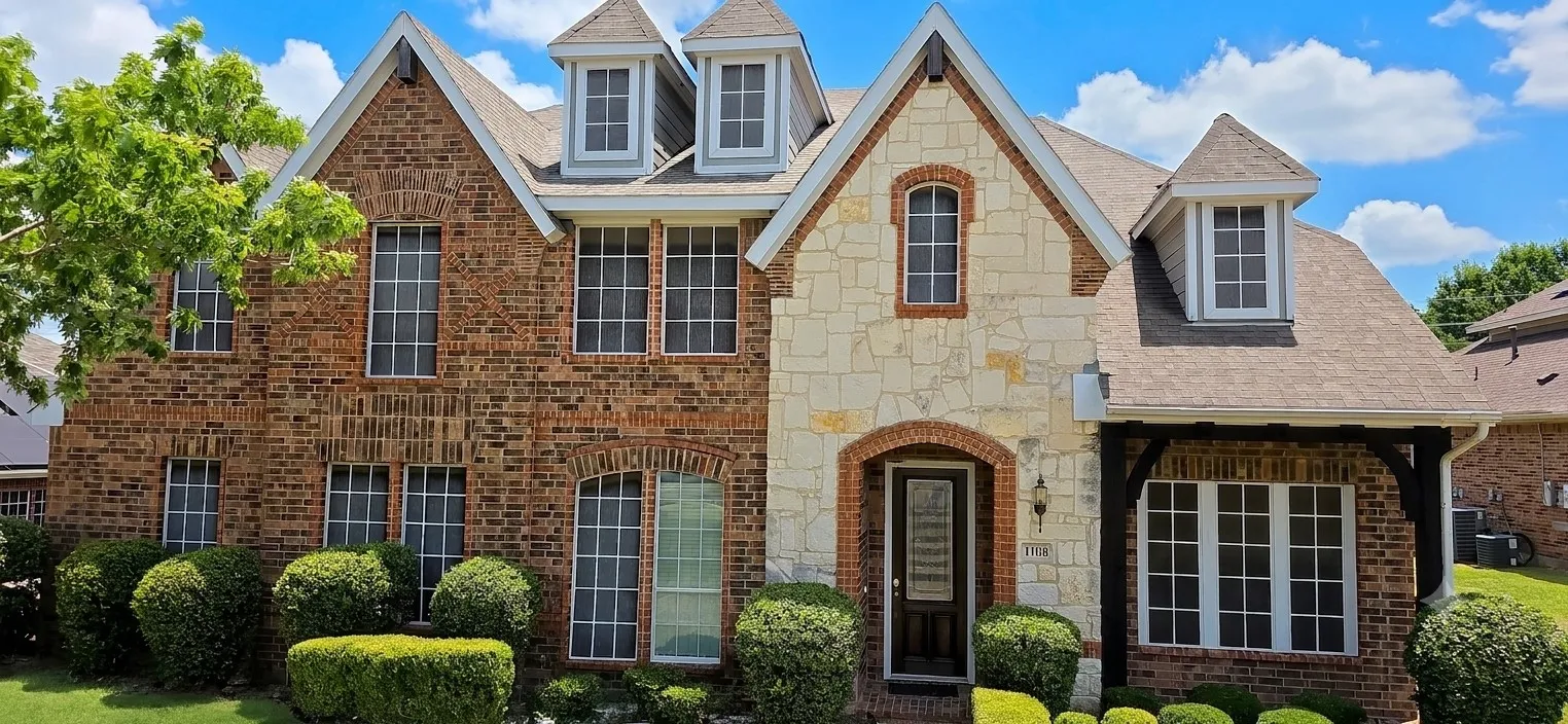 Two-story residence featuring a brick and stone facade with arched entryways and multiple gables