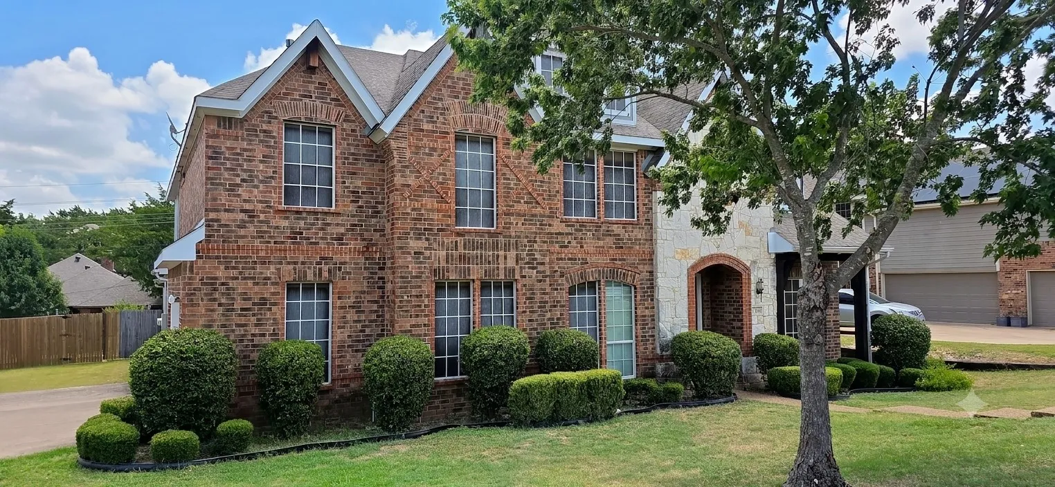 Brick and stone exterior featuring multiple gables, arched entry, and grid-pattern windows