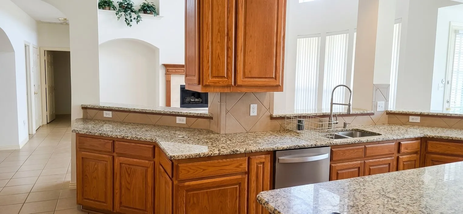 Kitchen featuring granite countertops, wood cabinetry, stainless steel dishwasher, and a double basin sink with a high-arc faucet