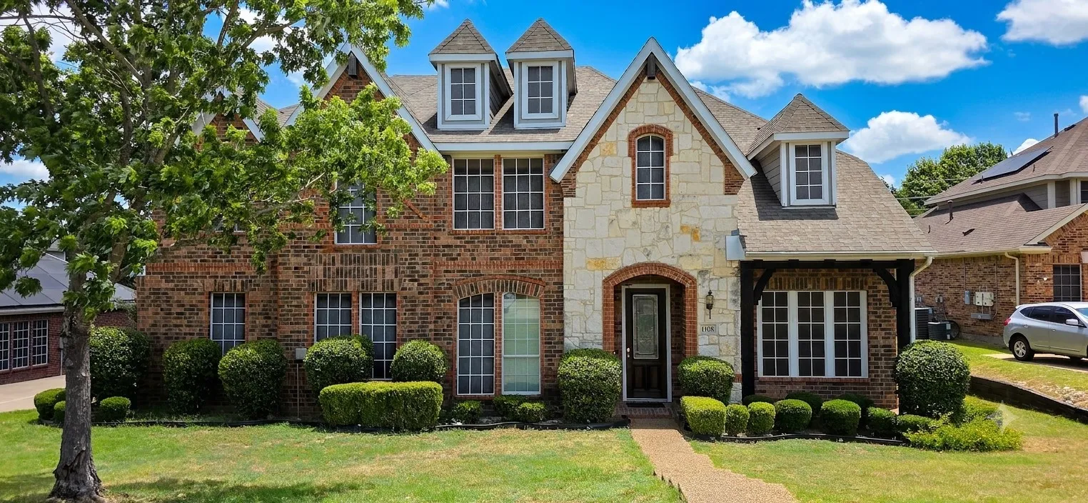 Brick and stone facade residence featuring multiple gabled dormers and a prominent entry