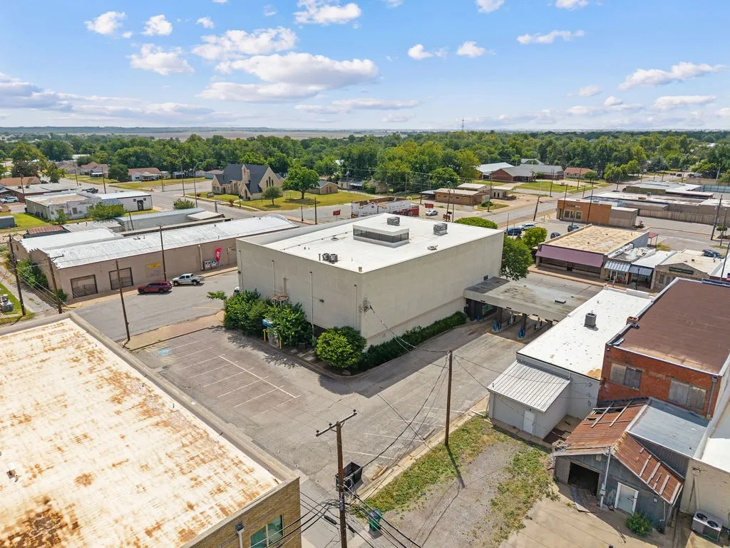 Commercial building featuring a flat roof, an expansive paved parking area, and a covered drive-through entrance