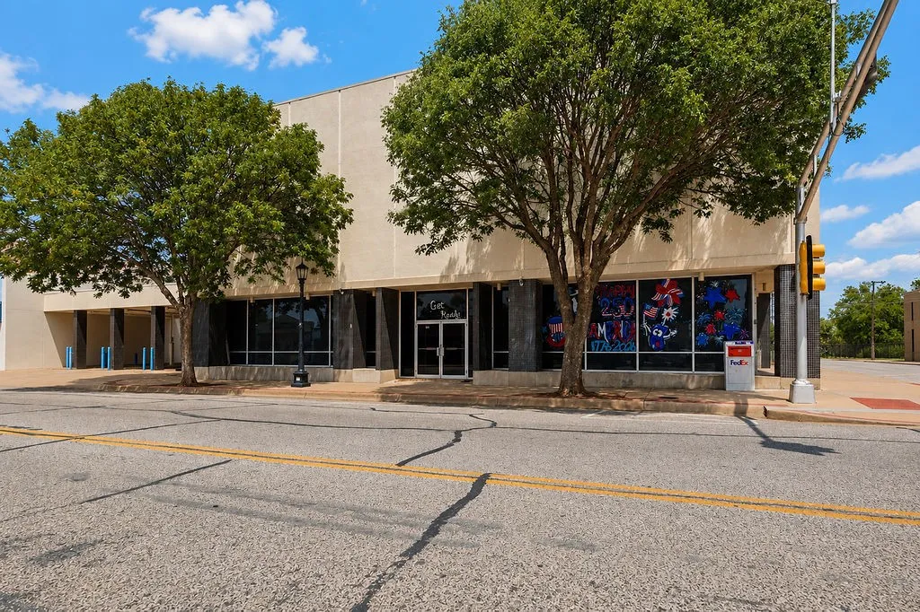 Commercial building featuring a cream-colored facade, expansive storefront windows, and a prominent double-door entry